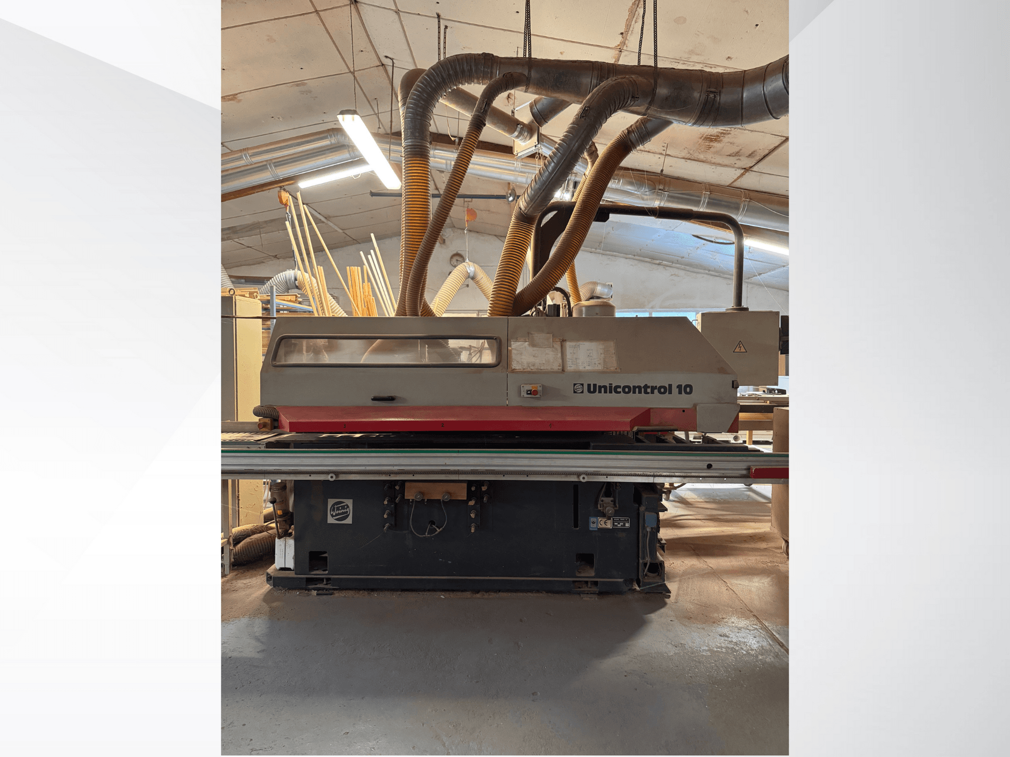 Вид спереди деревообрабатывающего станка Unicontrol 10 с трубками для удаления пыли и элементами управления.