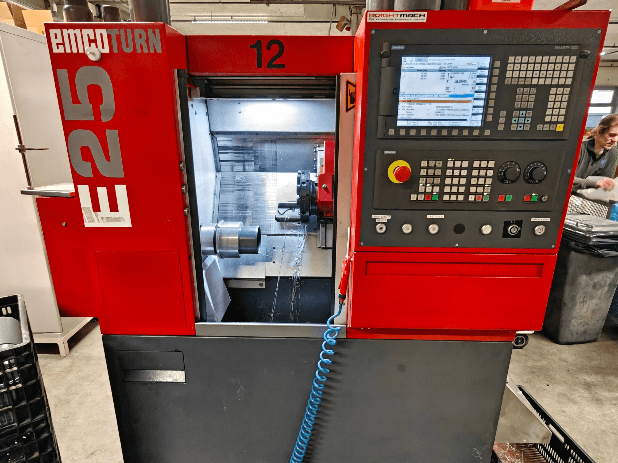 Вид спереди станка EMCO TURN E25: панель управления, держатель инструмента и внутреннее пространство с видимым режущим инструментом.