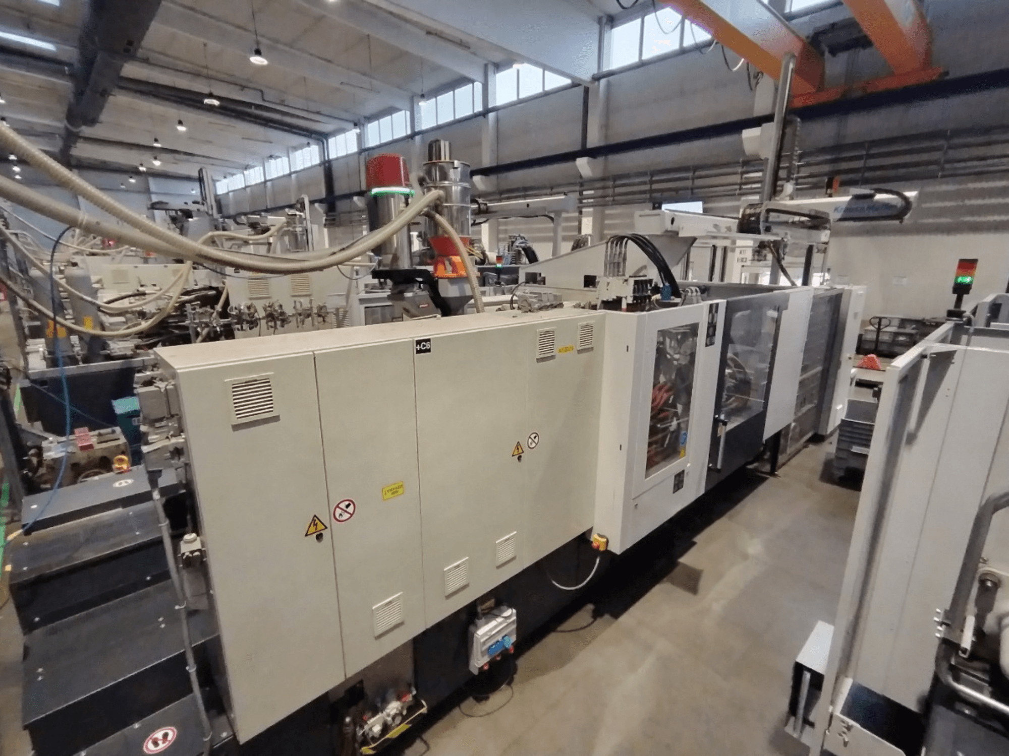 Промышленная машина для литья под давлением, показанная с боковой стороны, с панелью управления и предупреждениями о безопасности. Бренд: Неизвестно.