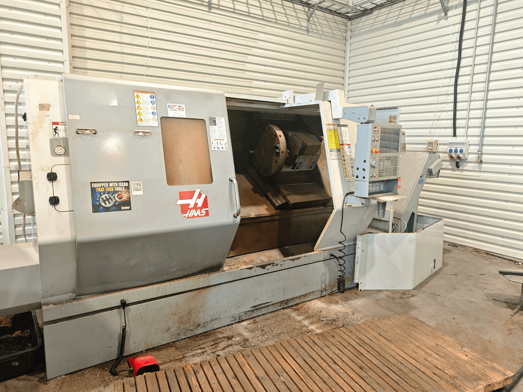 Горизонтальный токарный станок Haas SL-40HE, вид спереди, на котором видны панель управления, рабочая зона и предупреждающие надписи.