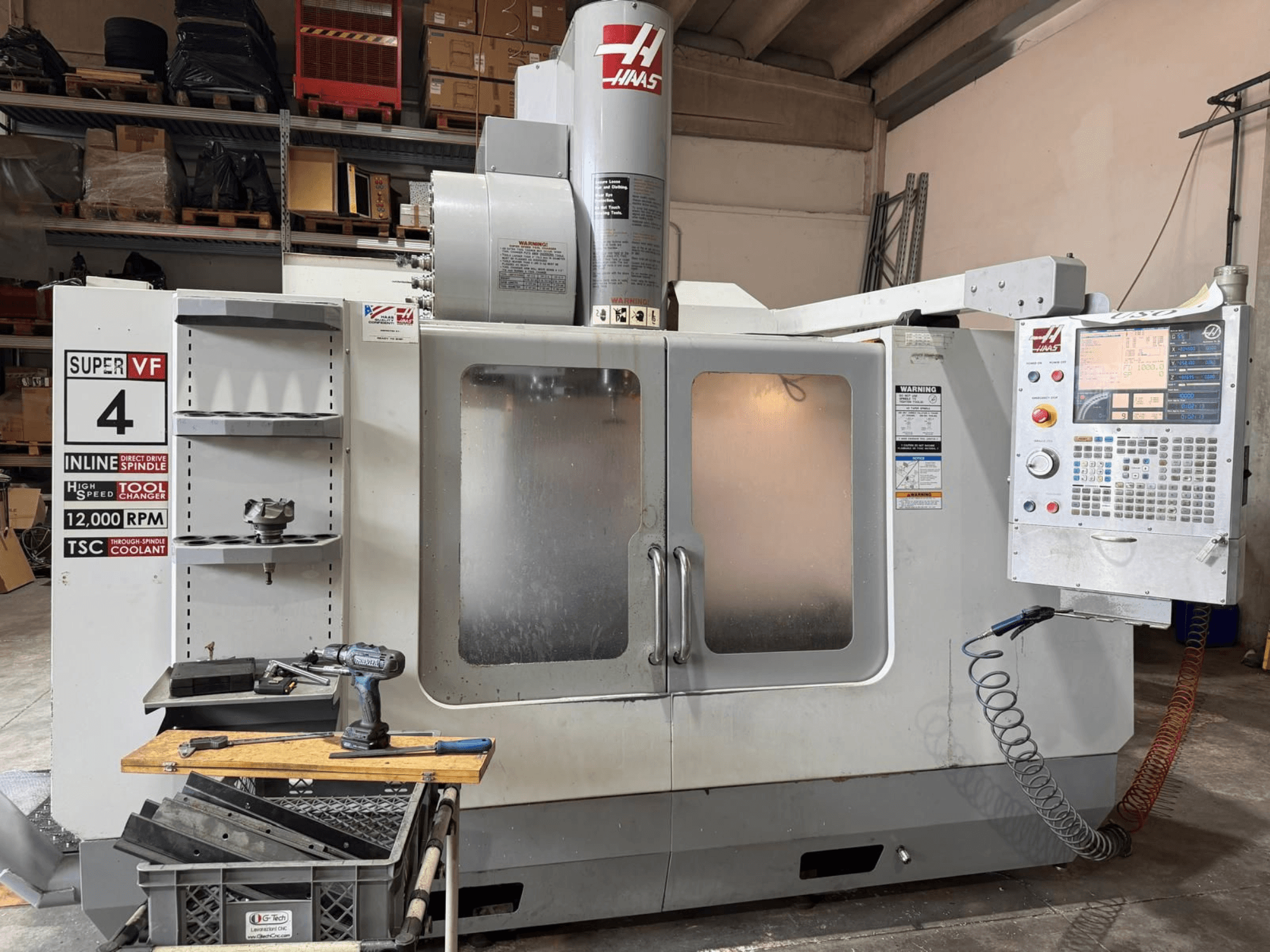 Вид спереди на вертикальный обрабатывающий центр HAAS VF-4SSHE с пультом управления, инструментальной стойкой и шпинделем со скоростью вращения 12 000 об/мин; высокоскоростной прецизионный станок.