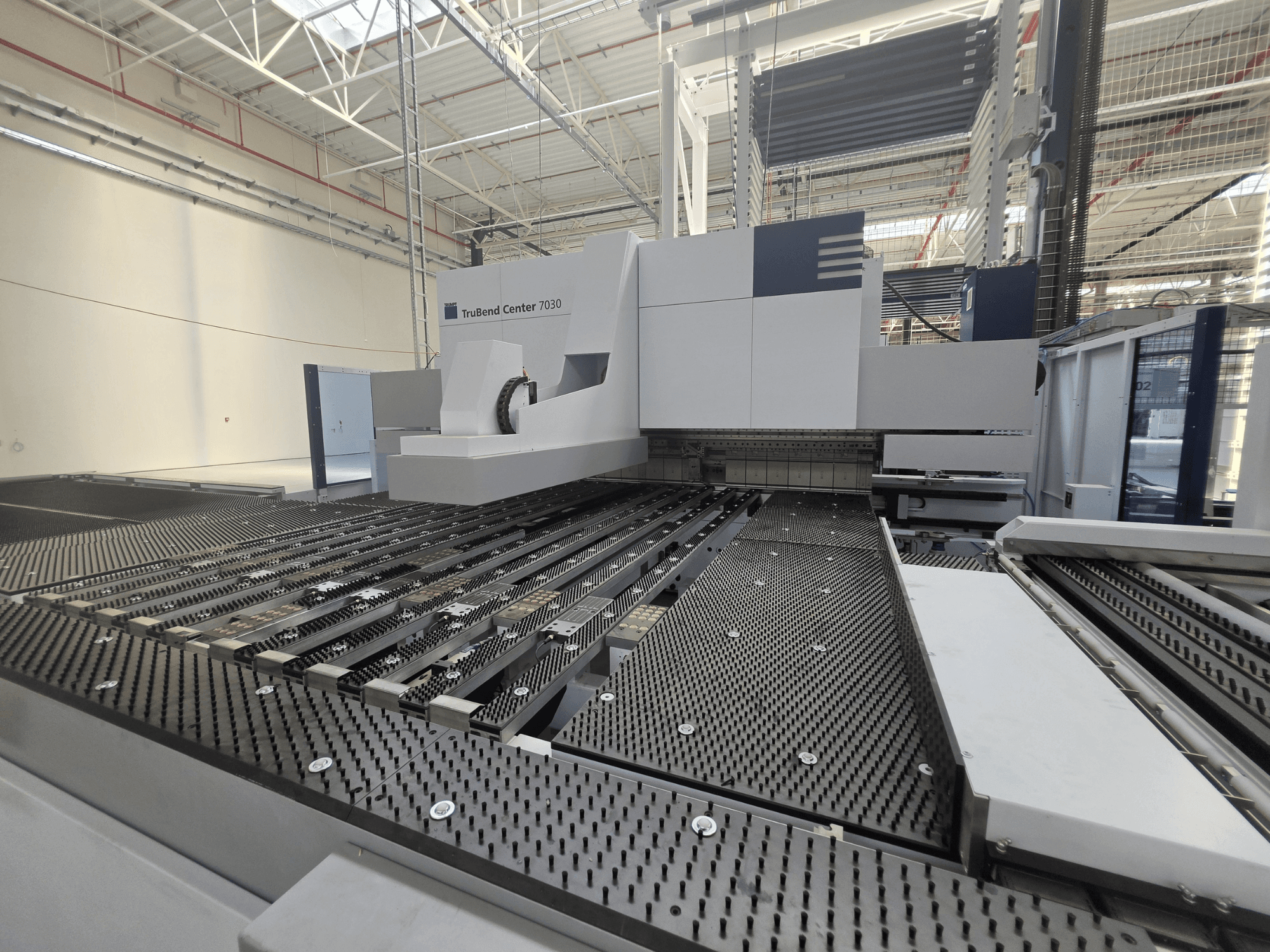 Гибочный станок TRUMPF TruBend Center 7030 в заводской комплектации, вид спереди, на котором видны сложная конструкция рабочего стола и гибочный рычаг.