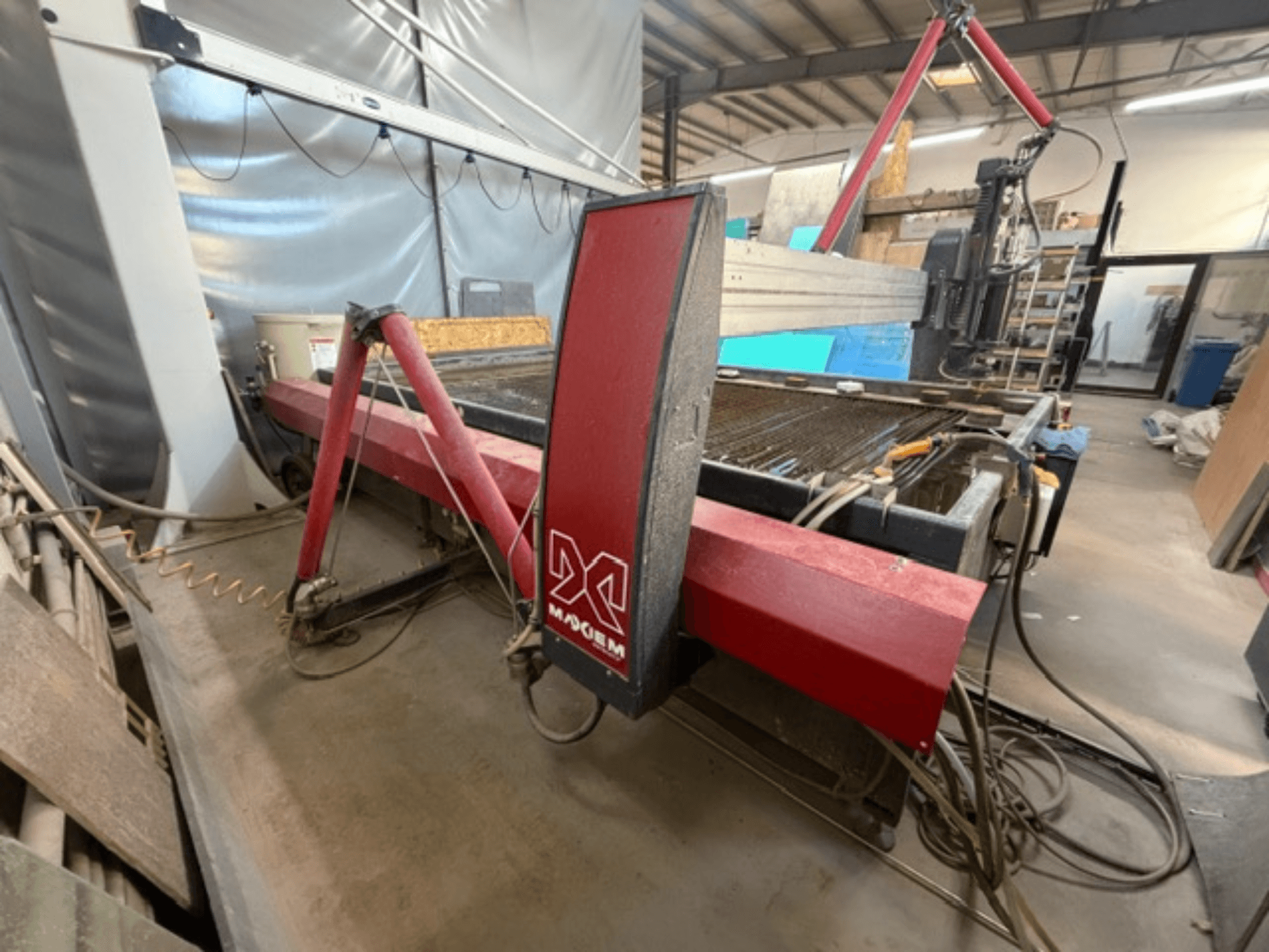 Красный станок гидроабразивной резки марки X, вид сбоку, с изображением механических компонентов и деталей трубопроводов.