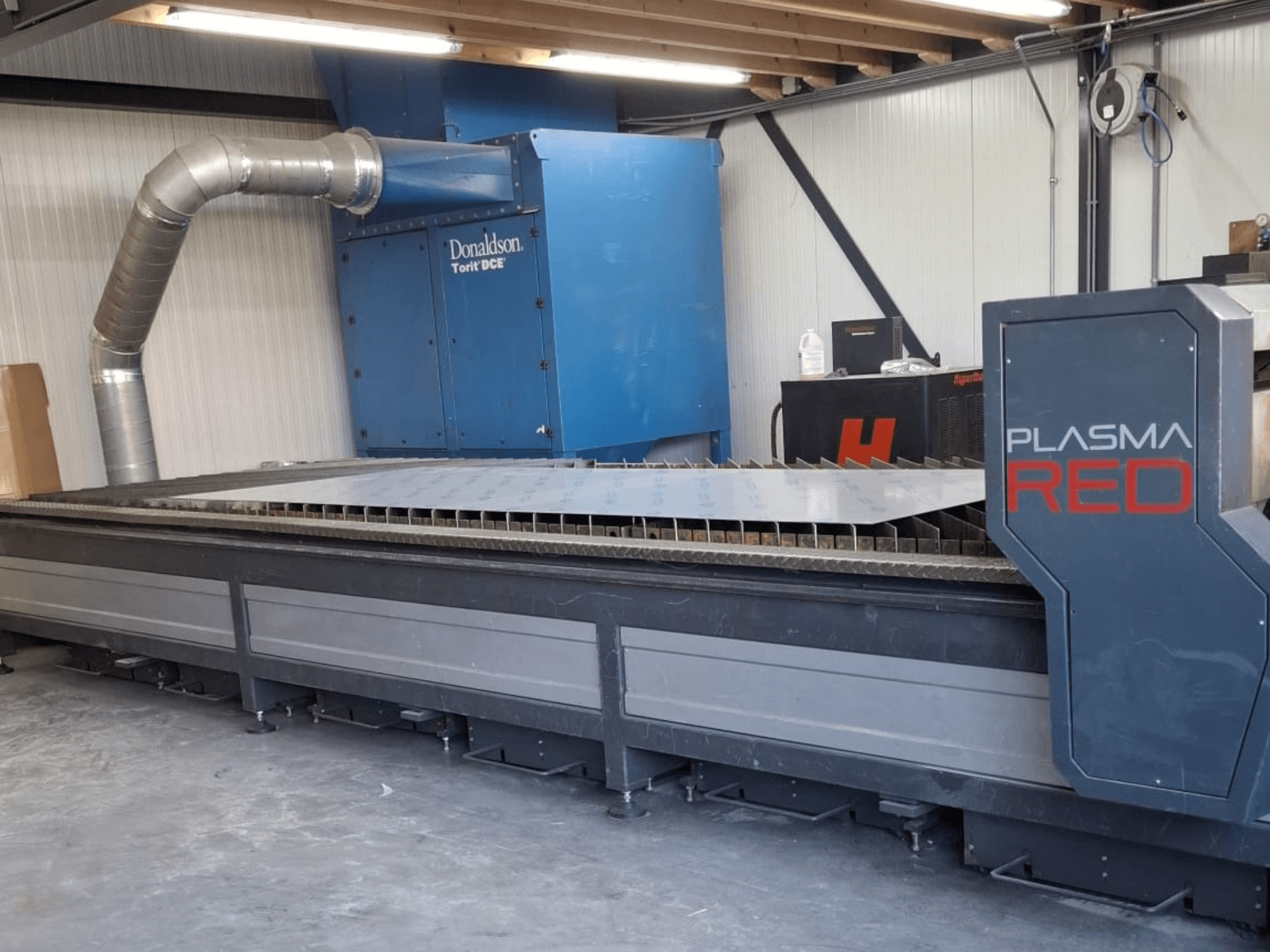 Машина плазменной резки SOITAAB Plasmatech-Red спереди, с широким столом для резки и вытяжной системой.
