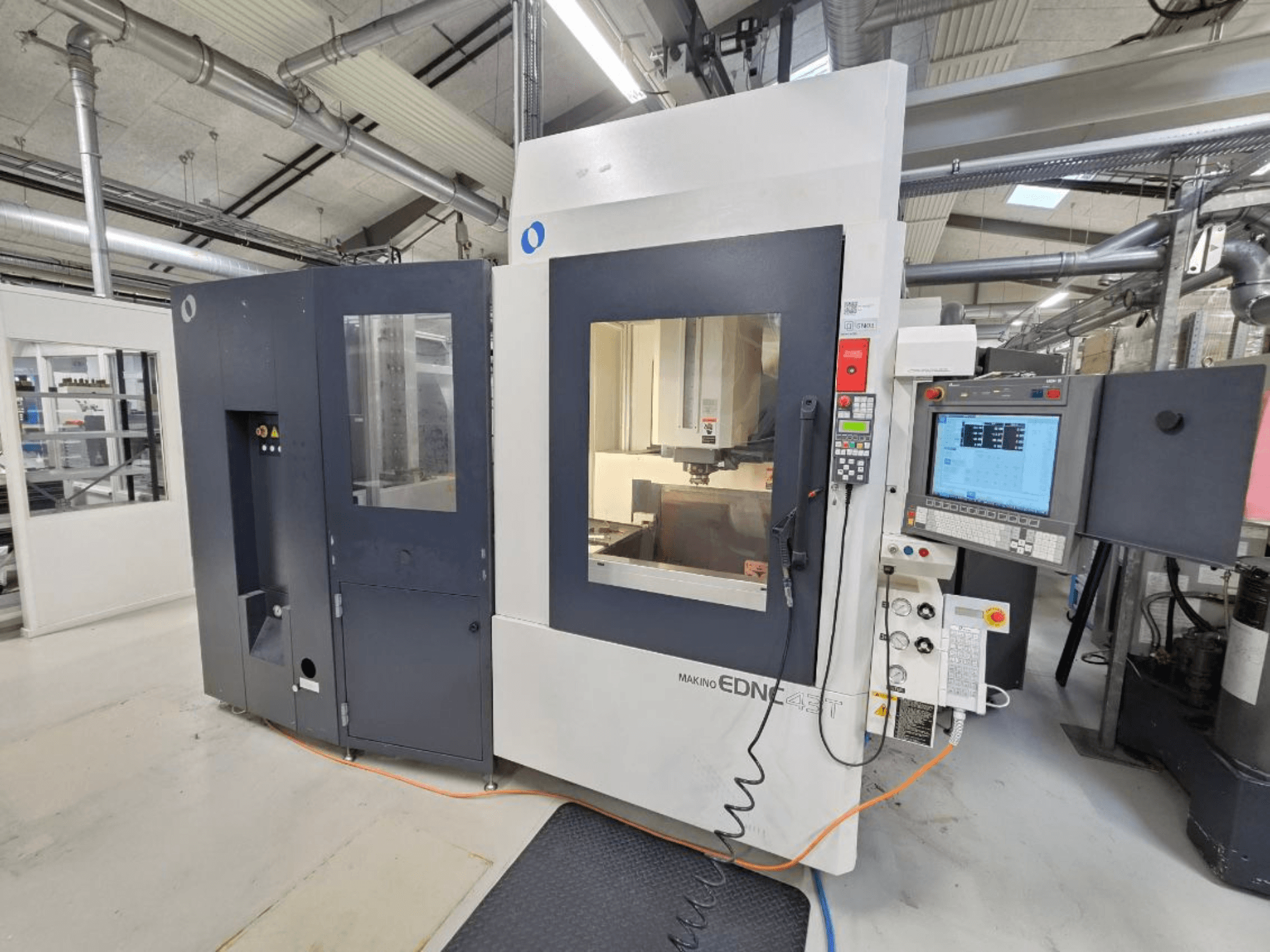 Вид спереди на электроэрозионный станок с погружным электродом Makino EDNC 43T с роботом Erowa, пультом управления и открытой рабочей зоной.