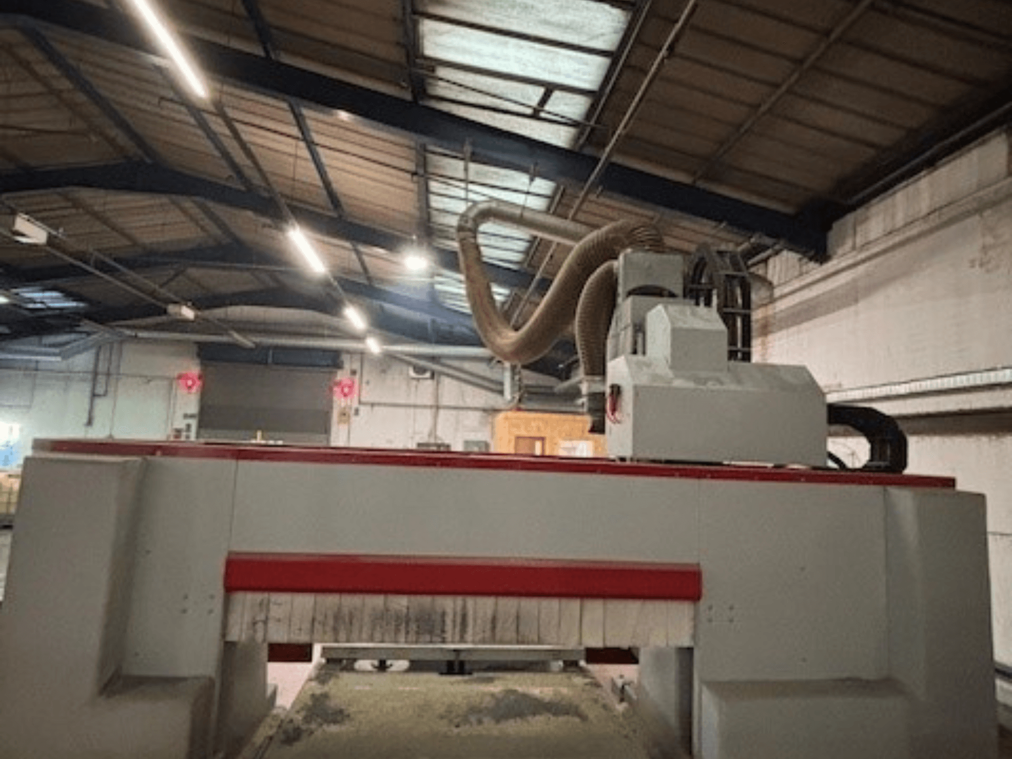 Фрезерный станок с ЧПУ в мастерской, вид сбоку, подчеркивающий красно-серый дизайн, система пылеудаления прилагается.