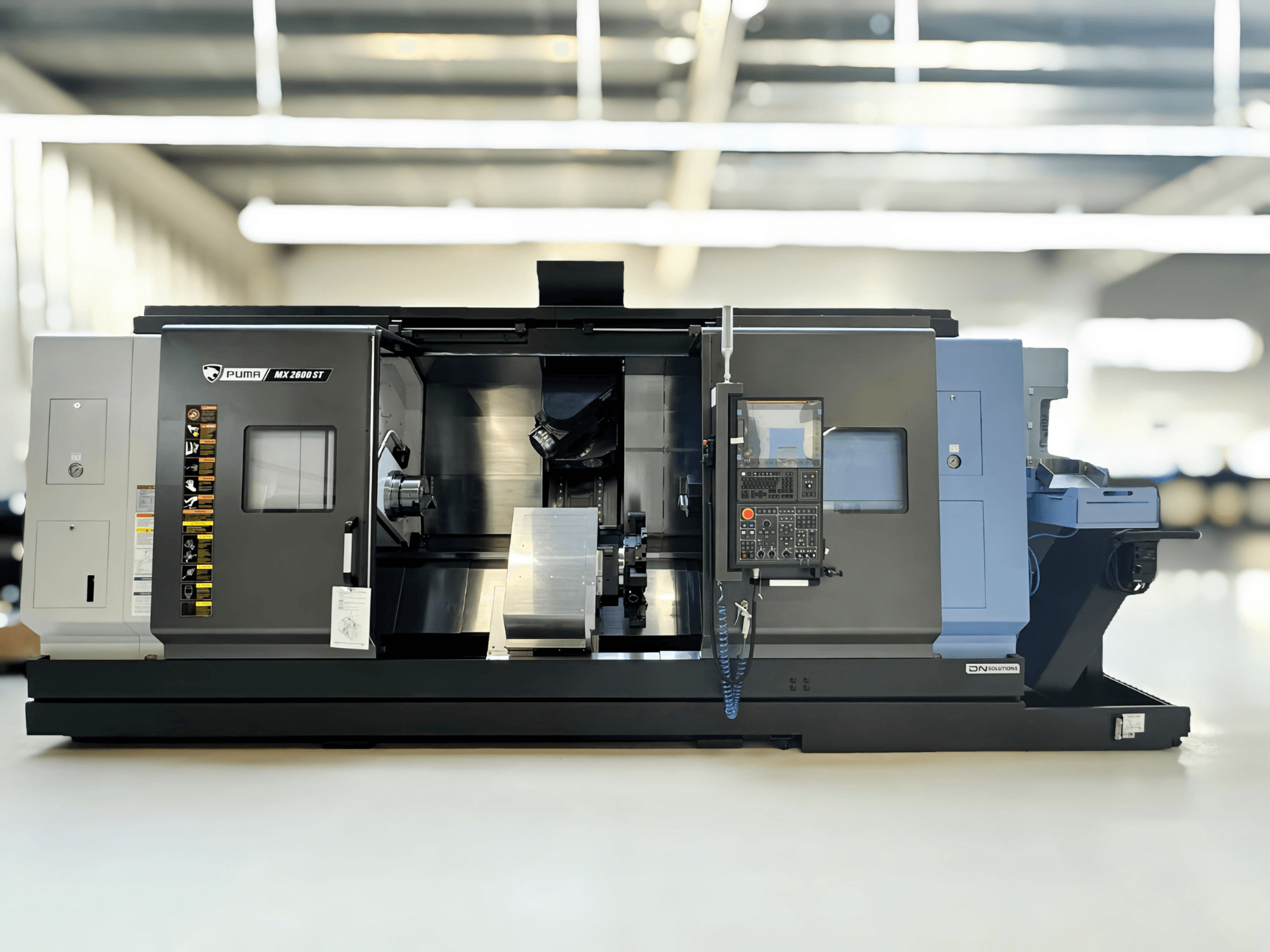Фрезерно-поворотный центр Puma MX2600ST с видом сбоку, с детально проработанной панелью управления и зоной обработки с видимыми инструментами.