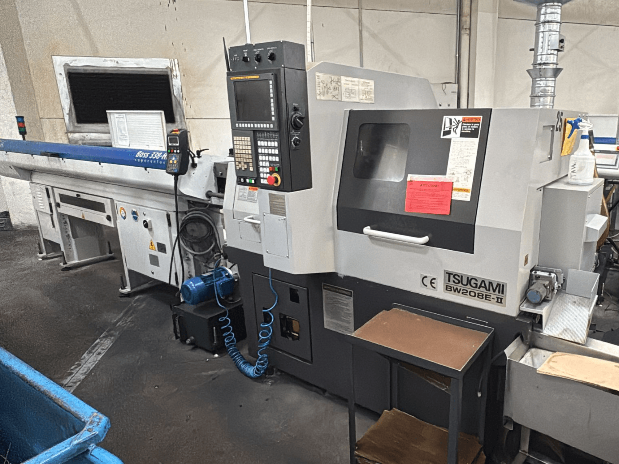 Станок с ЧПУ Tsugami BW208E-II в мастерской, показан с переднего ракурса, видна панель управления и защитные наклейки.