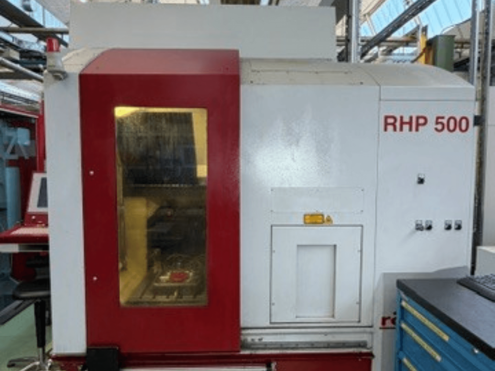 Вертикальный обрабатывающий центр Röders TEC RHP 500, вид спереди, на котором видны панель управления и прозрачное окно, позволяющее увидеть внутреннюю часть станка.