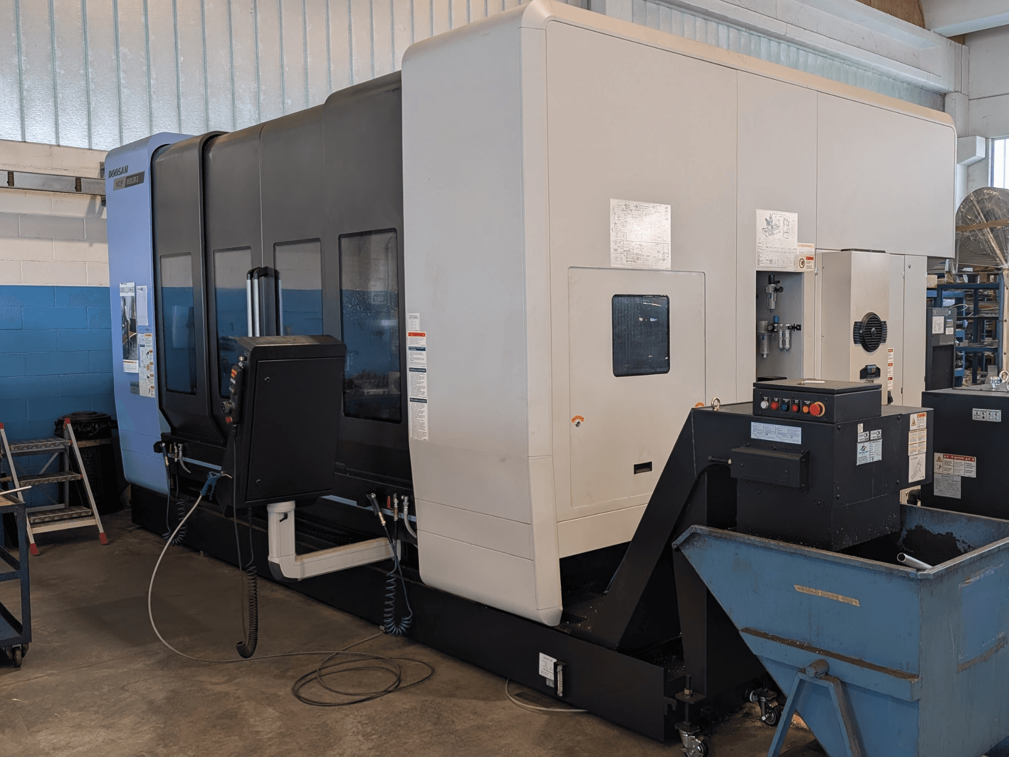 Вертикальный обрабатывающий центр DOOSAN VCF850LSR-II в боковом ракурсе: на снимке видны панель управления, система подачи охлаждающей жидкости и прочная конструкция.