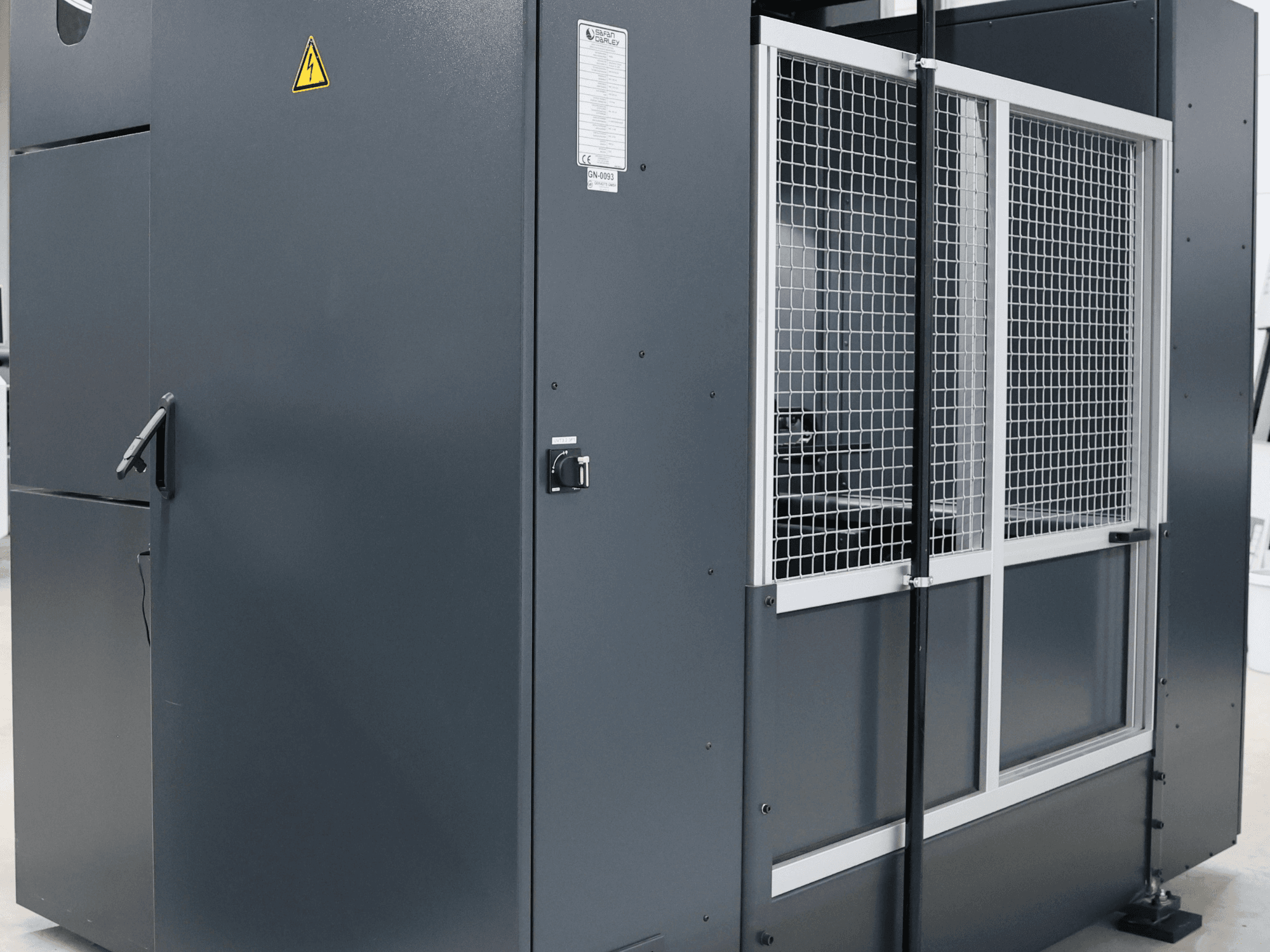 Серая промышленная машина с предупреждением о безопасности, вид спереди с сетчатой дверцей и панелью управления, модель с надписью.