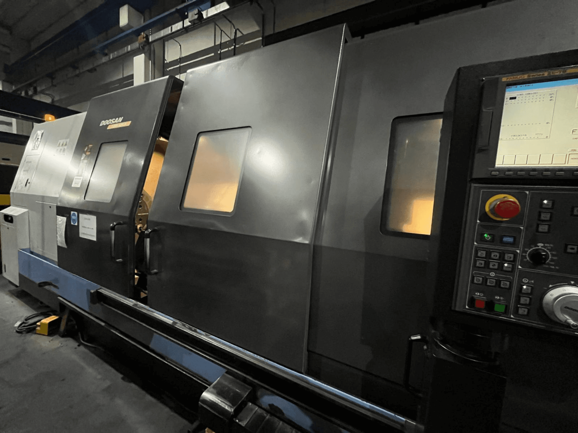 Токарный станок с ЧПУ Doosan с видом спереди, с панелью управления и интерфейсом оператора с видимым цифровым дисплеем и кнопками.
