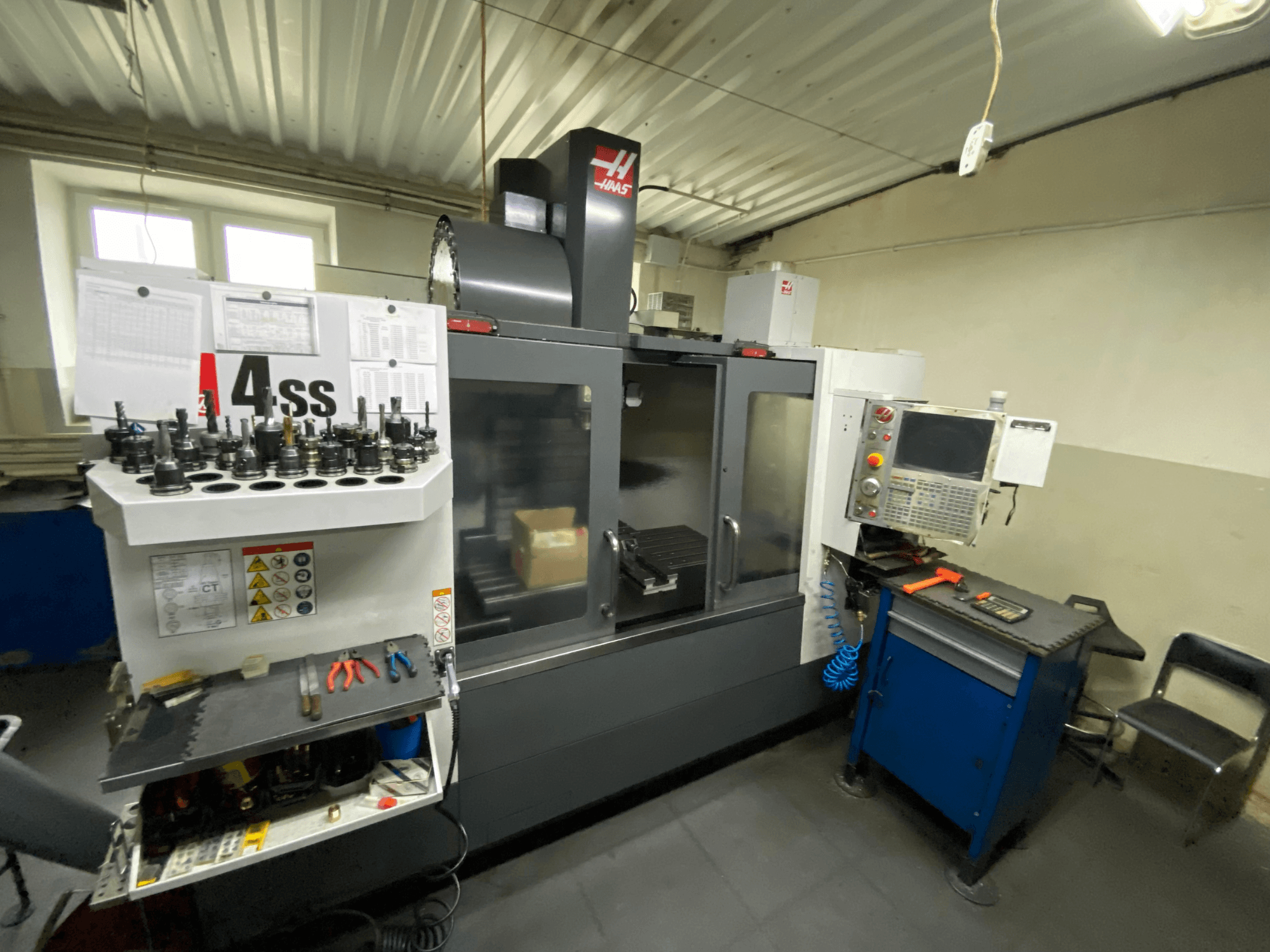 Вертикальный обрабатывающий центр Haas VF-4SS, вид спереди с держателями инструментов и панелью управления. Видны установленные инструменты и рабочая зона.