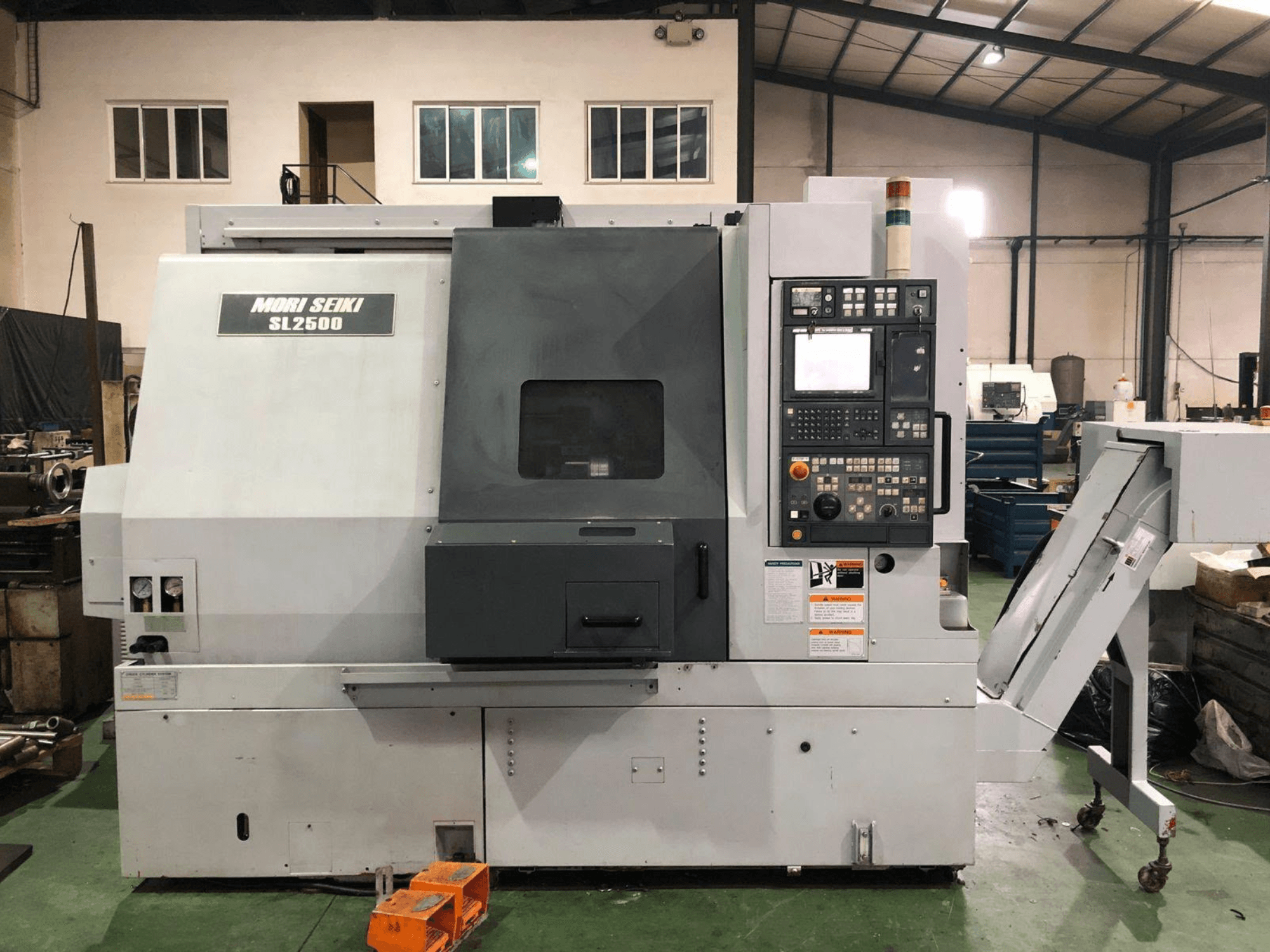 Токарно-фрезерный центр DMG Mori Seiki SL 2500 Y, вид сбоку, на котором видны панель управления и конвейер для отвода стружки.