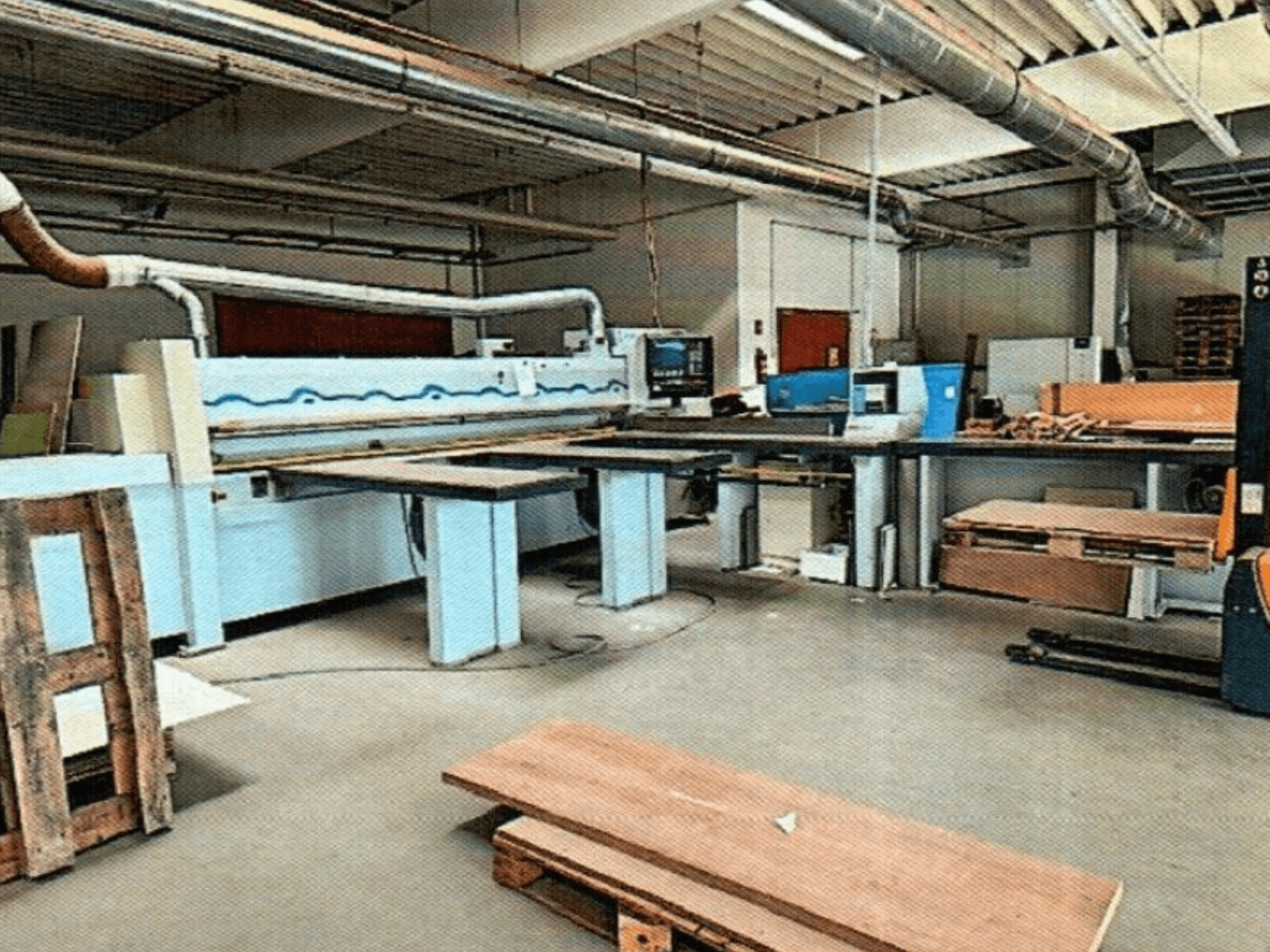 Панельная пила HOMAG HPL 11/38/22 в мастерской, с большим столом для резки и консолью для демонстрации, вид спереди.