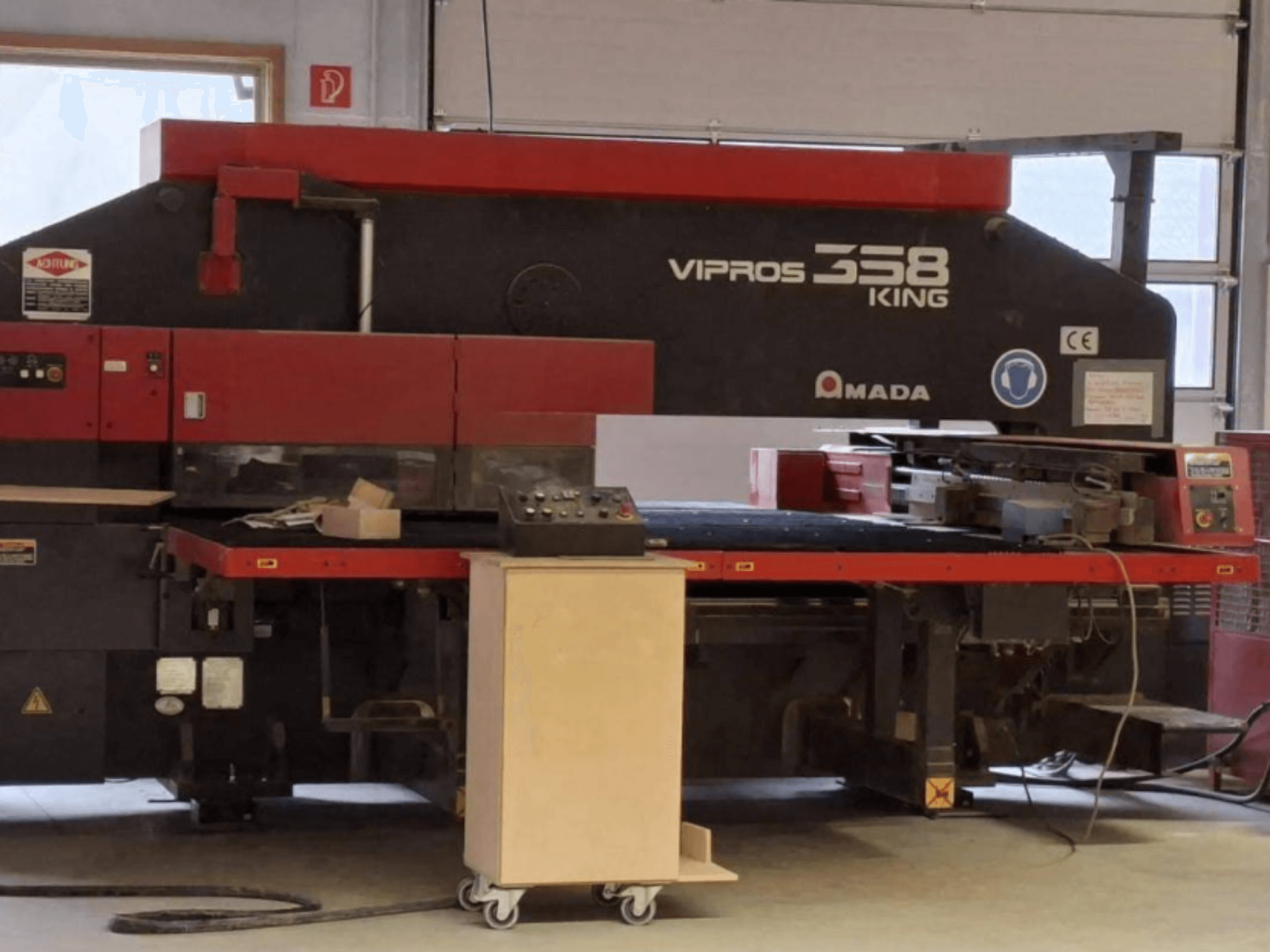 Штамповочный пресс с ЧПУ AMADA VIPROS 358 KING в боковом ракурсе, с панелью управления и зоной хранения инструментов.
