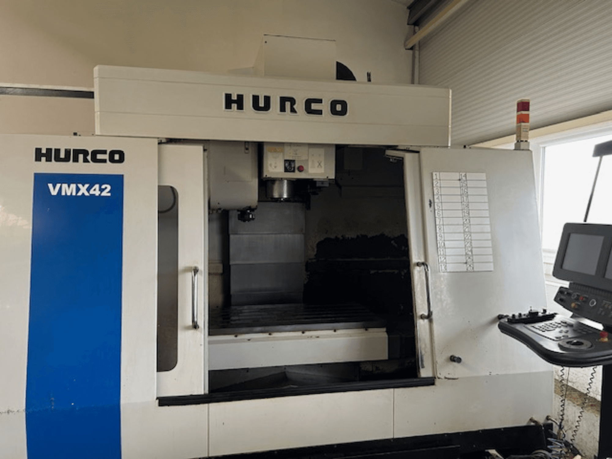 Станок с ЧПУ Hurco VMX42 с видом спереди, показывает панель управления, шпиндель и рабочую зону; демонстрирует операционную схему.