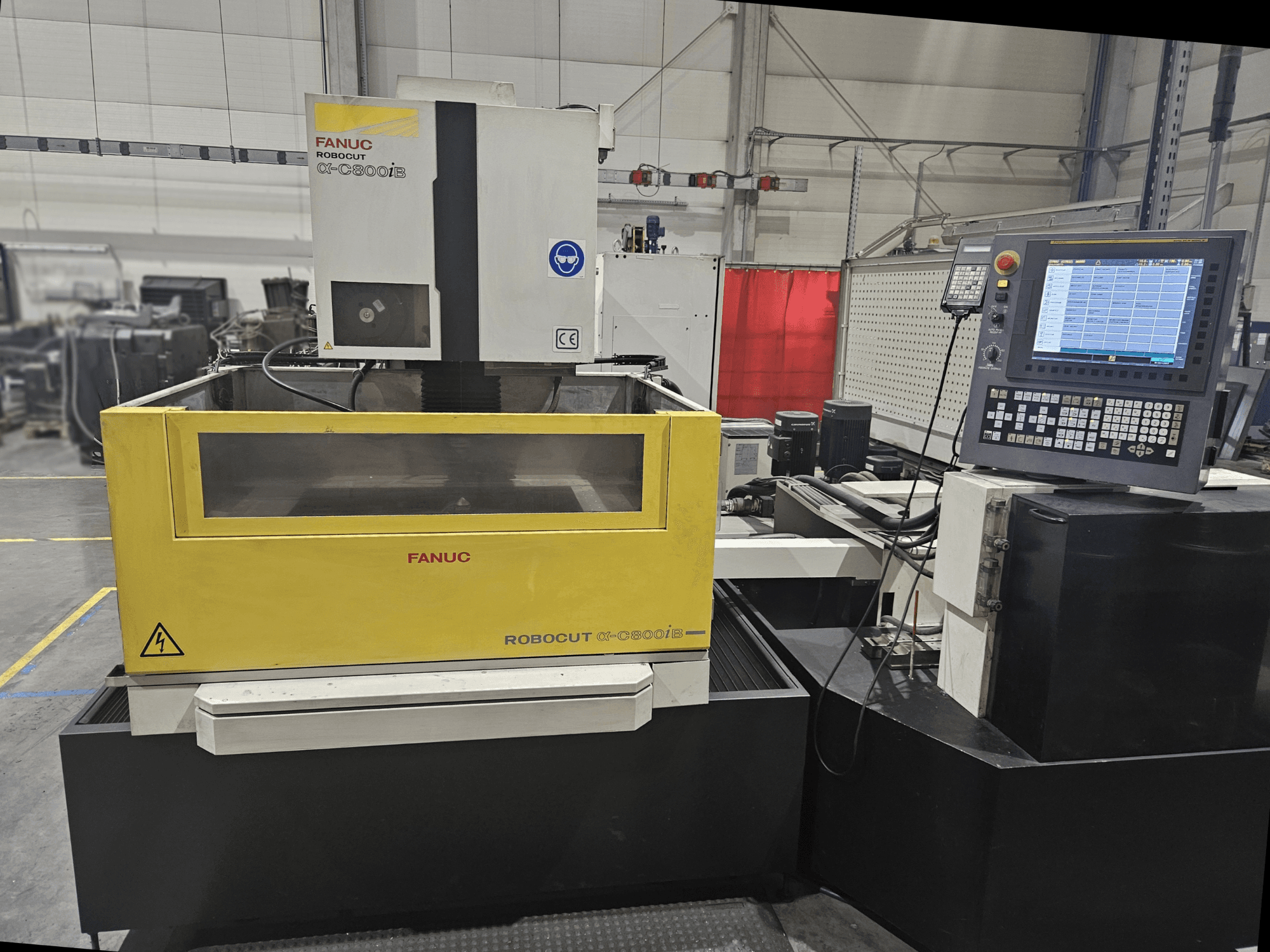 Вид спереди на FANUC Robocut α-C600iB с желто-серым корпусом станка, панелью управления ЧПУ и операционным дисплеем.