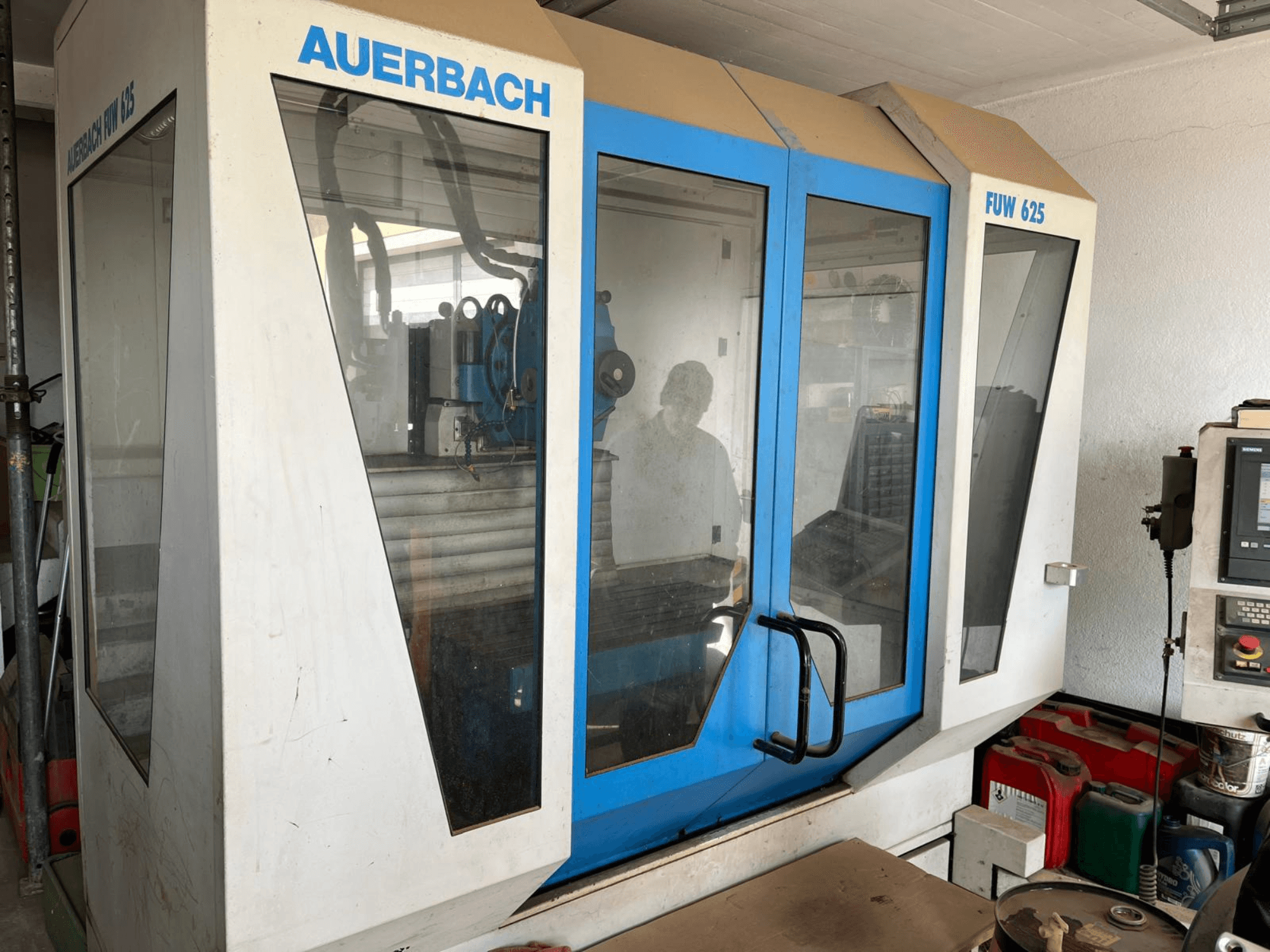 Универсальный обрабатывающий центр Auerbach FUW 625 с видом сбоку, со стеклянными панелями и панелью управления справа.