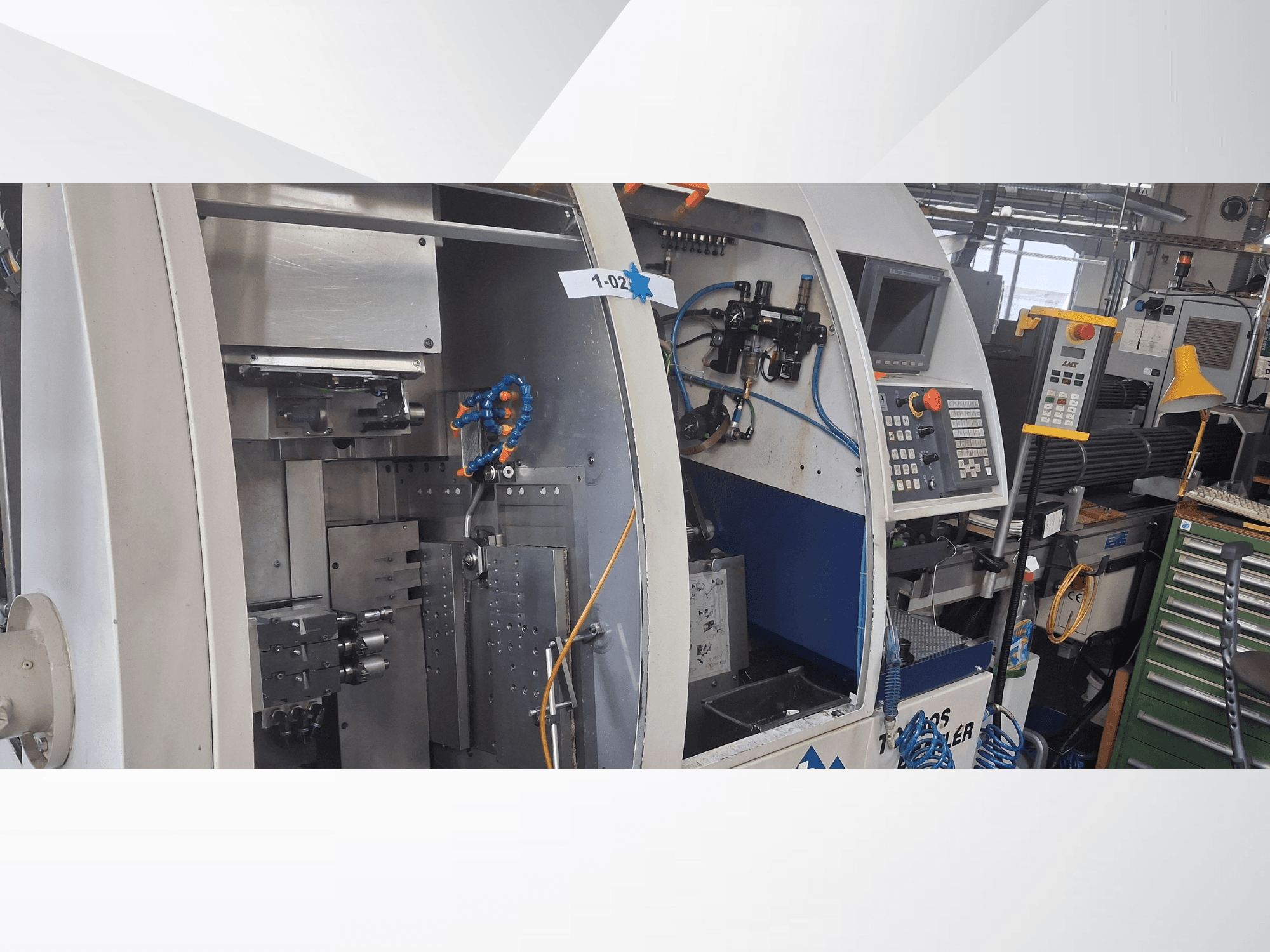 Токарный станок швейцарского типа TORNOS DECO 2000-10, вид спереди, показывающий панель управления, механизм вращения и внутреннюю настройку.