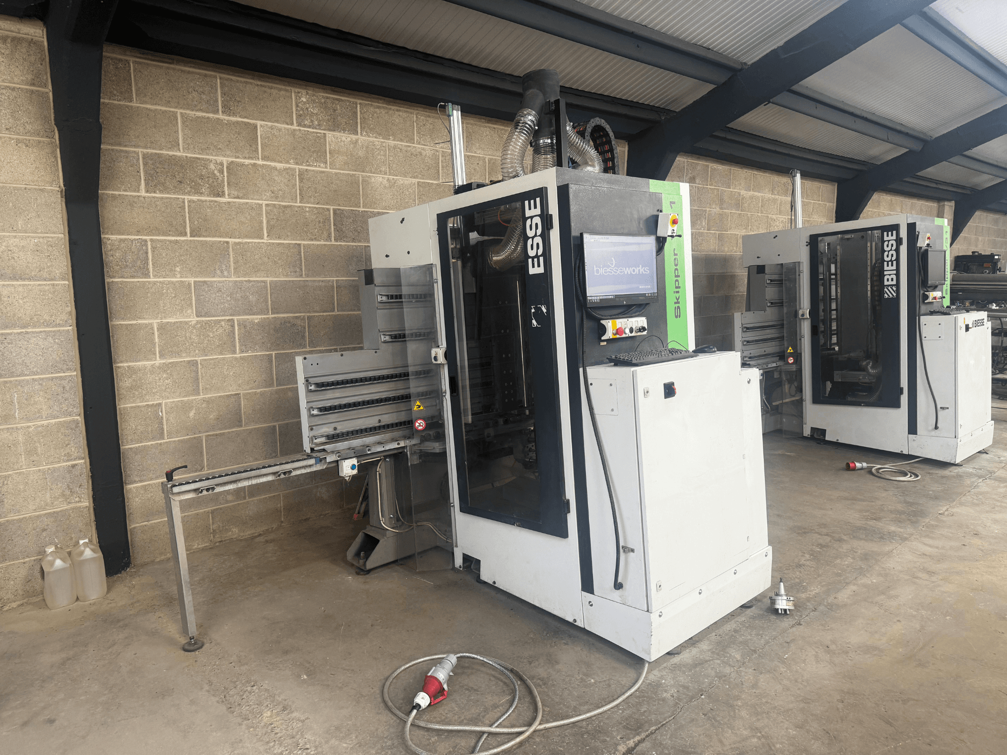 Сверлильный станок по дереву BIESSE Skipper v31 с видом сбоку, с панелью управления и соседними механизмами, в мастерской.