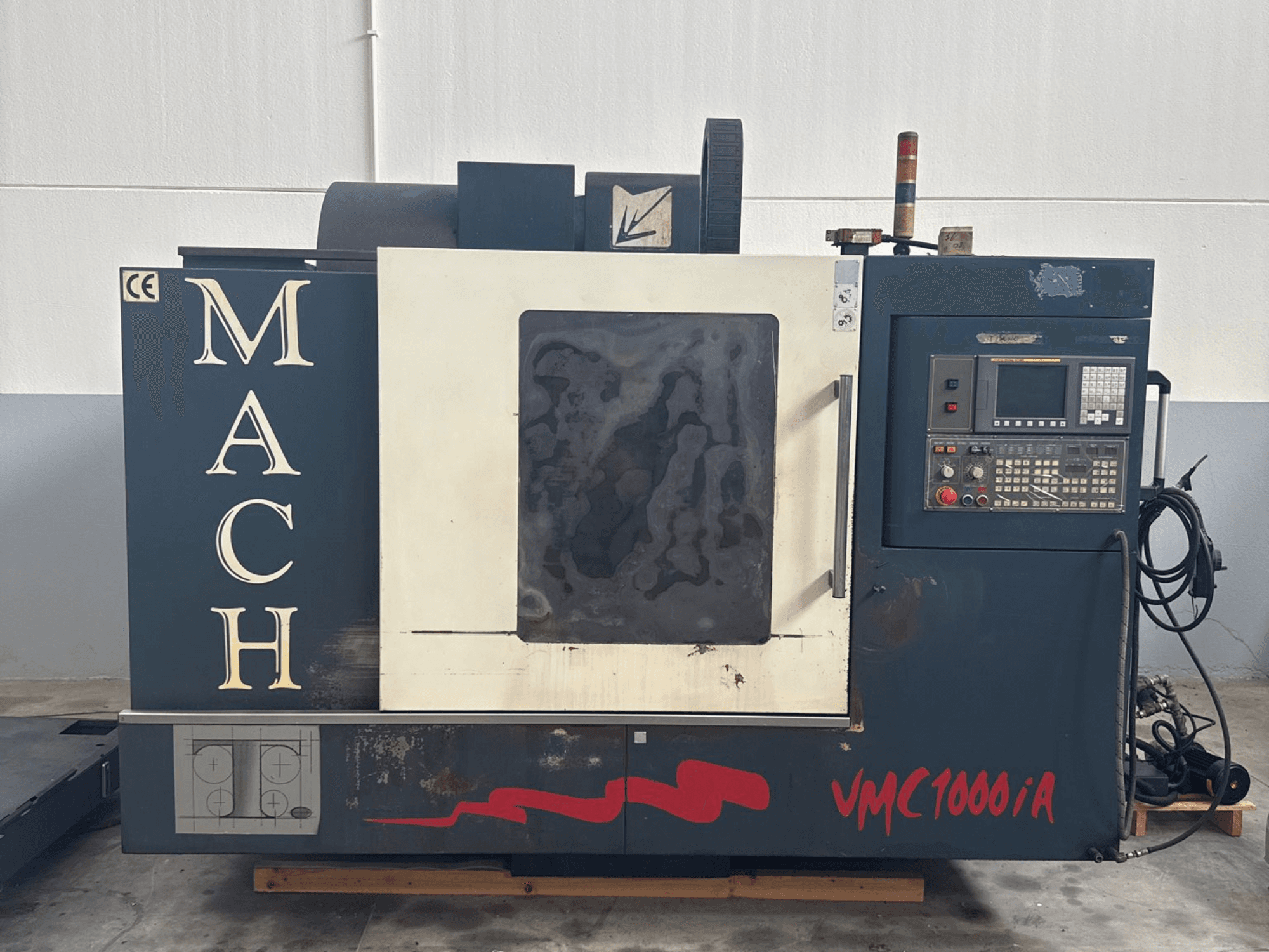 Вертикальный обрабатывающий центр MIND MACH VMC 1000/A на виде спереди, панель управления, шпиндель и маркировка основания.