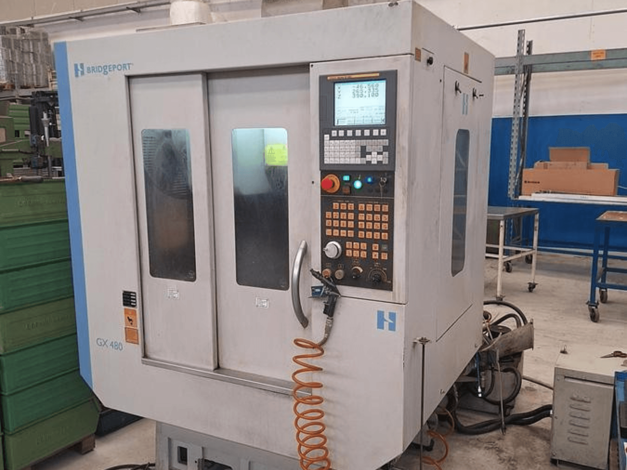Вертикальный обрабатывающий центр Bridgeport GX 480 на виде спереди, с панелью управления, двумя стеклянными дверцами и гибким шлангом.