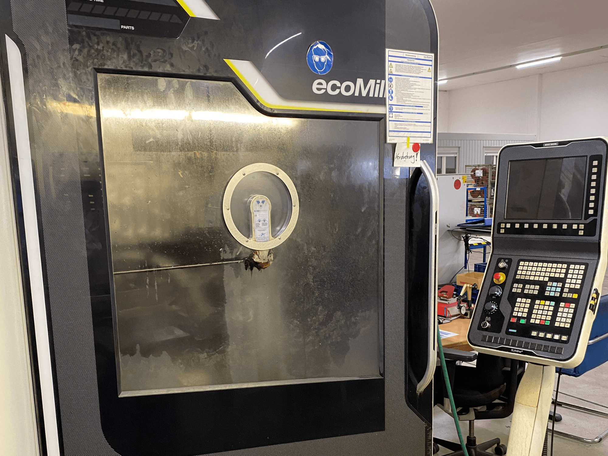 Фрезерный станок DMG MU 70 ECO, вид спереди: справа расположена панель управления, а через стеклянную панель видны внутренние компоненты.