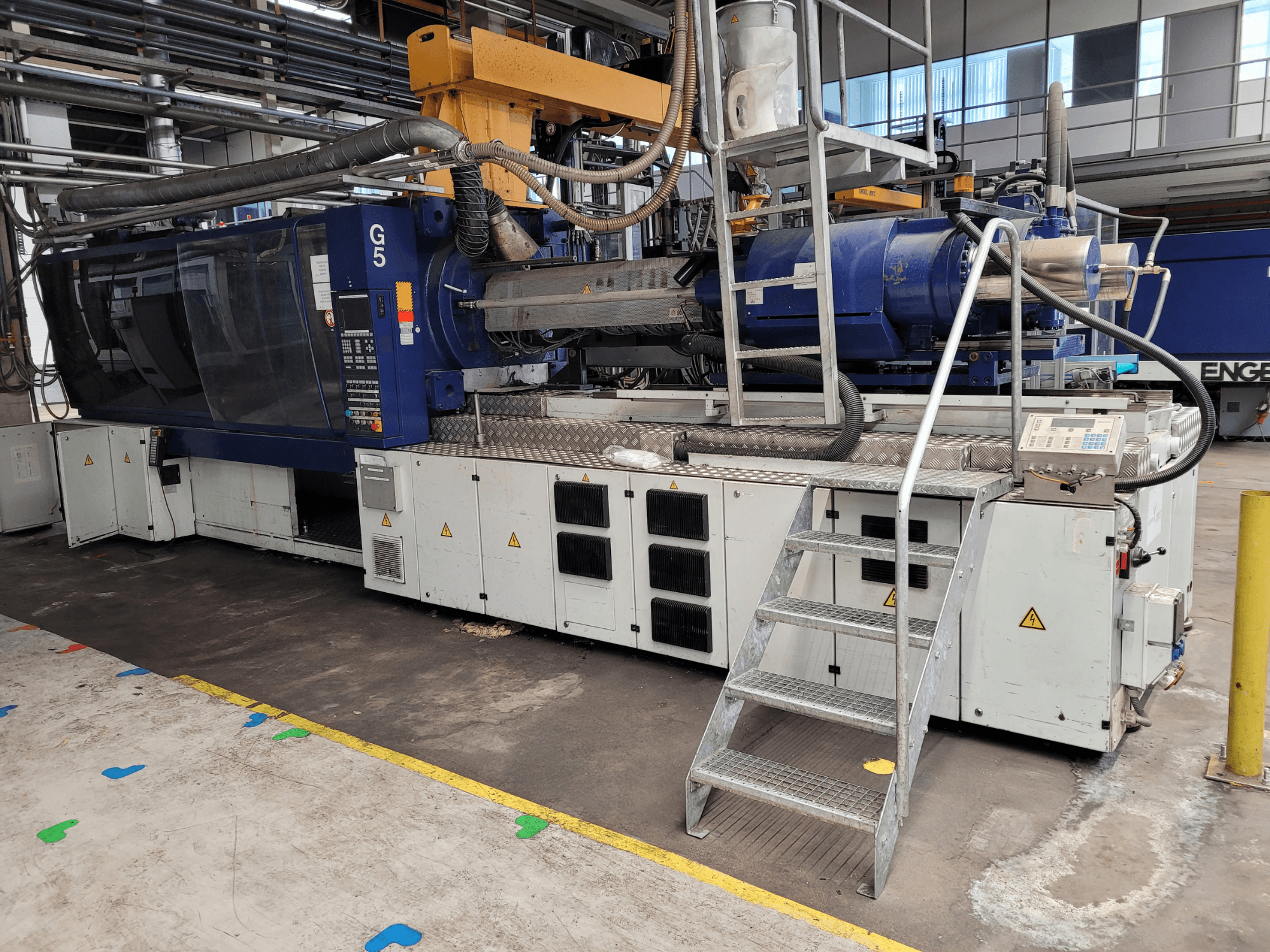 Машина для литья под давлением G5, вид сбоку, видны панель управления, стремянка и рабочая поверхность из нержавеющей стали.