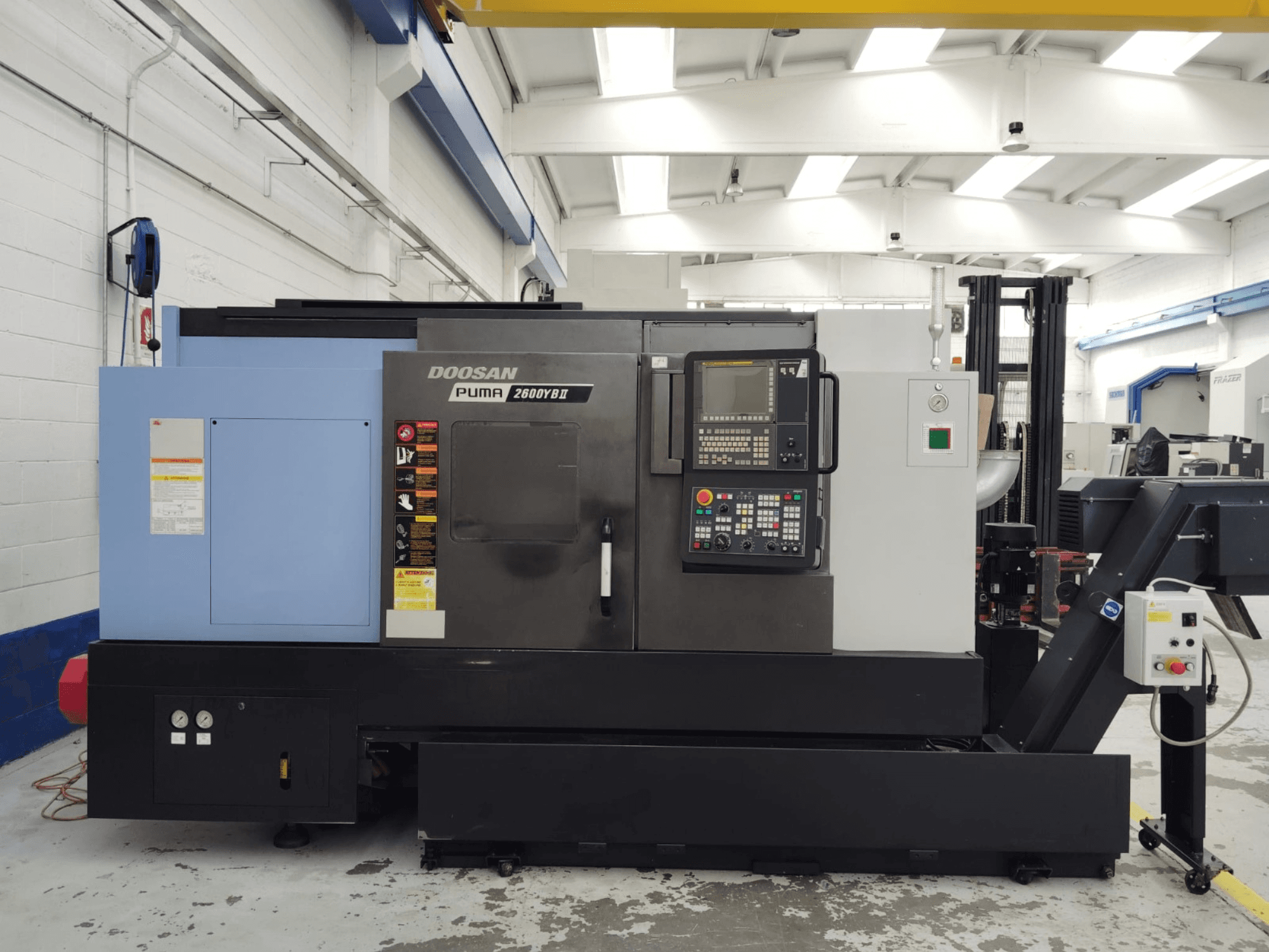 Вид спереди горизонтального токарного станка DOOSAN Puma 2600YB II с панелью управления и наклейками безопасности.