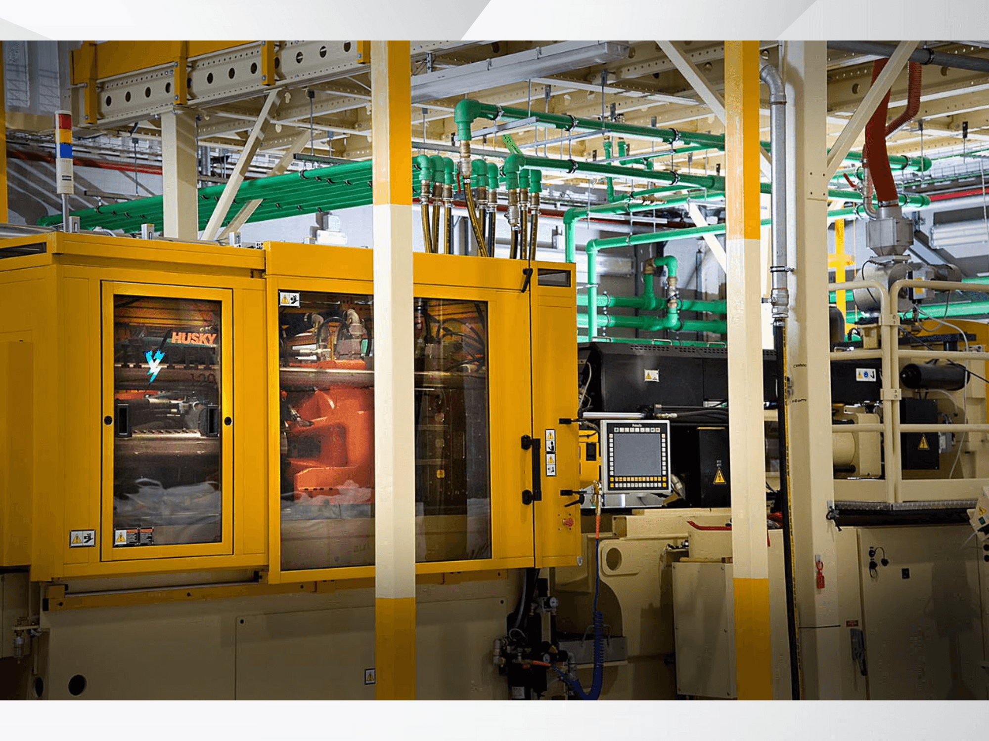 Промышленная машина Husky желтого цвета, вид спереди, демонстрирующая панель управления и внутренние механизмы на фоне завода.