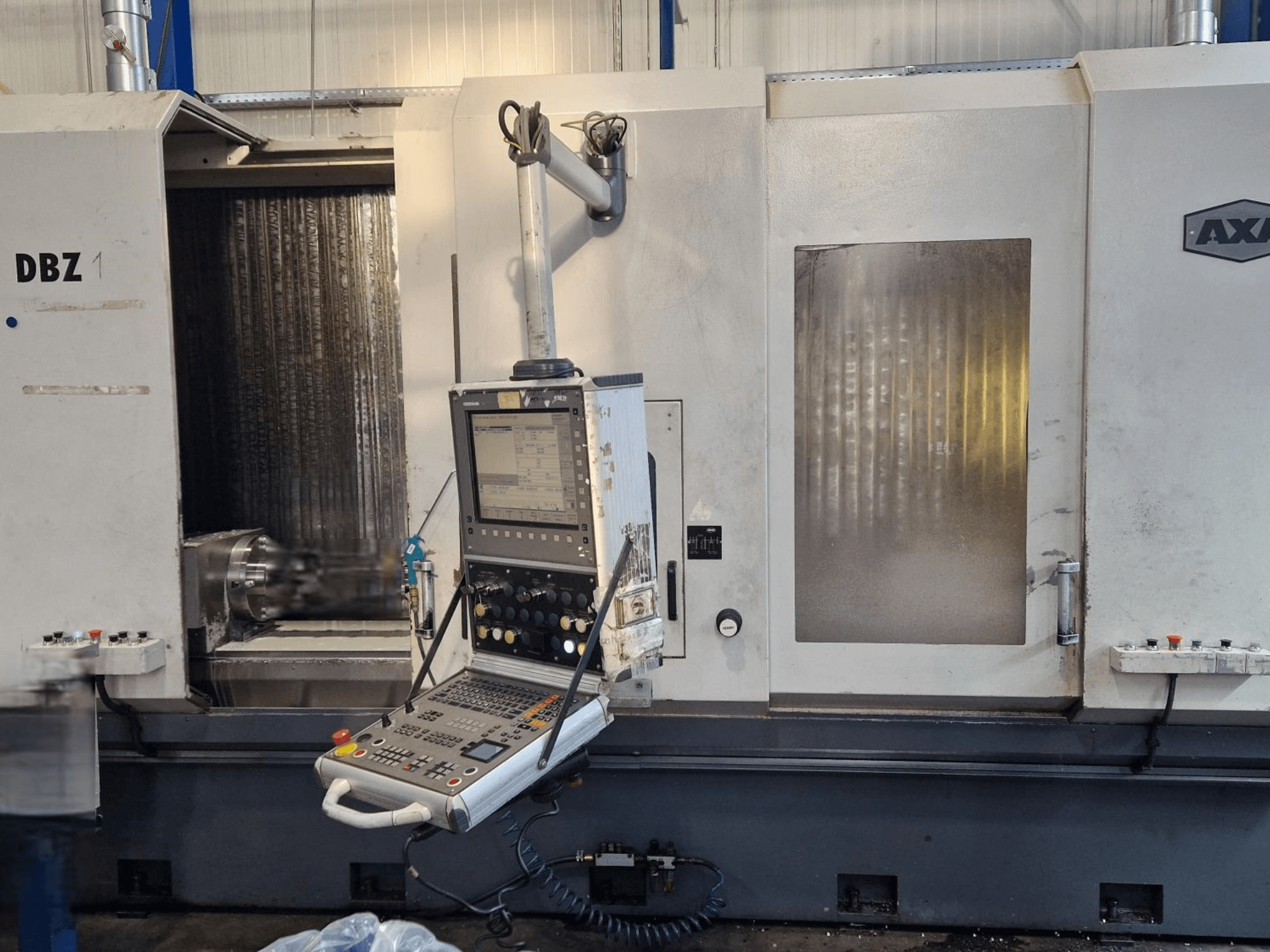 Вертикальный обрабатывающий центр AXA DBZ с угловым видом спереди, с панелью управления и видимой зоной режущего инструмента.
