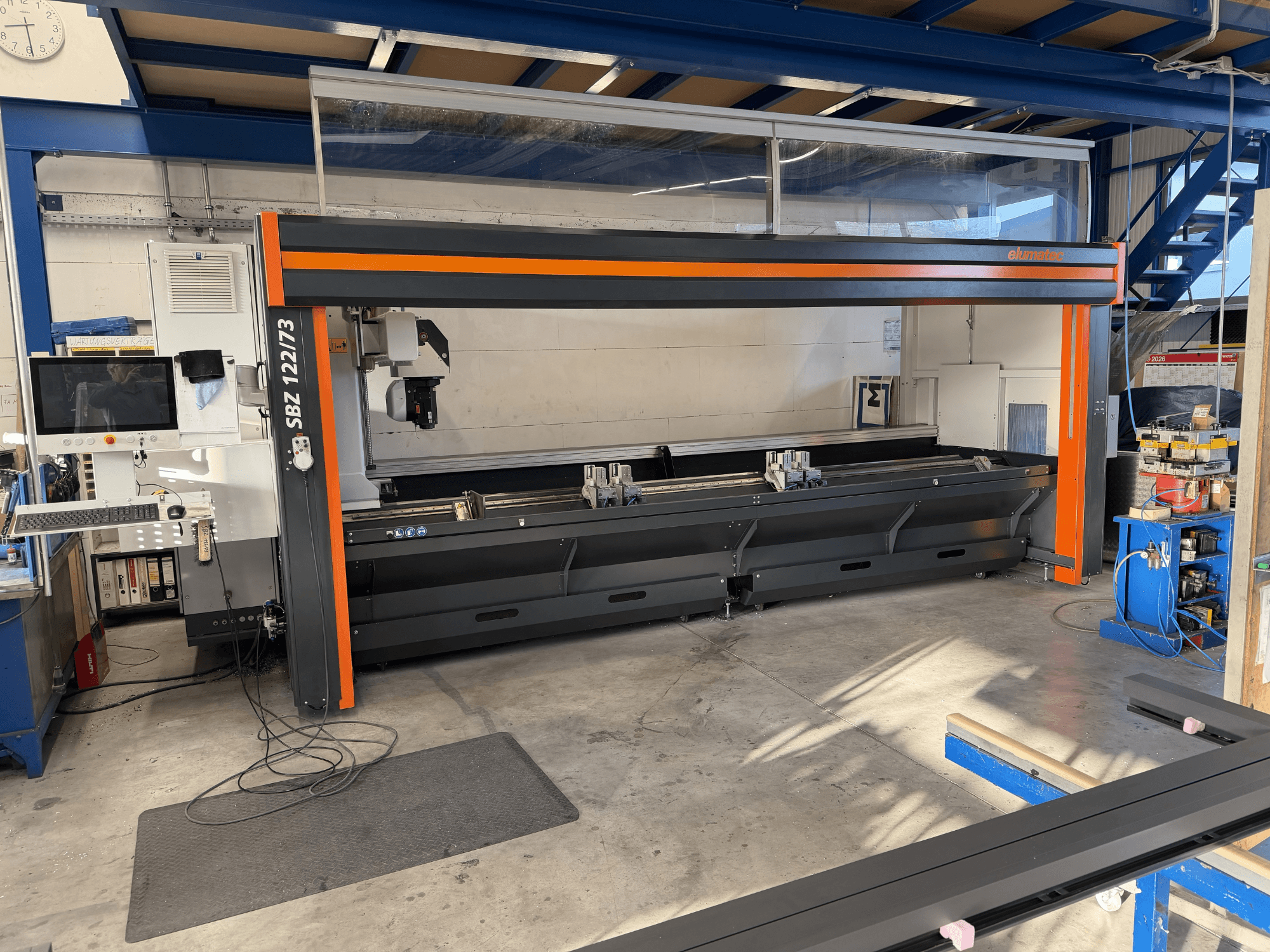 Станок Elumatec SBZ 122/73 на виде спереди, демонстрирует панель управления, зону резки и расположение рабочего пространства.