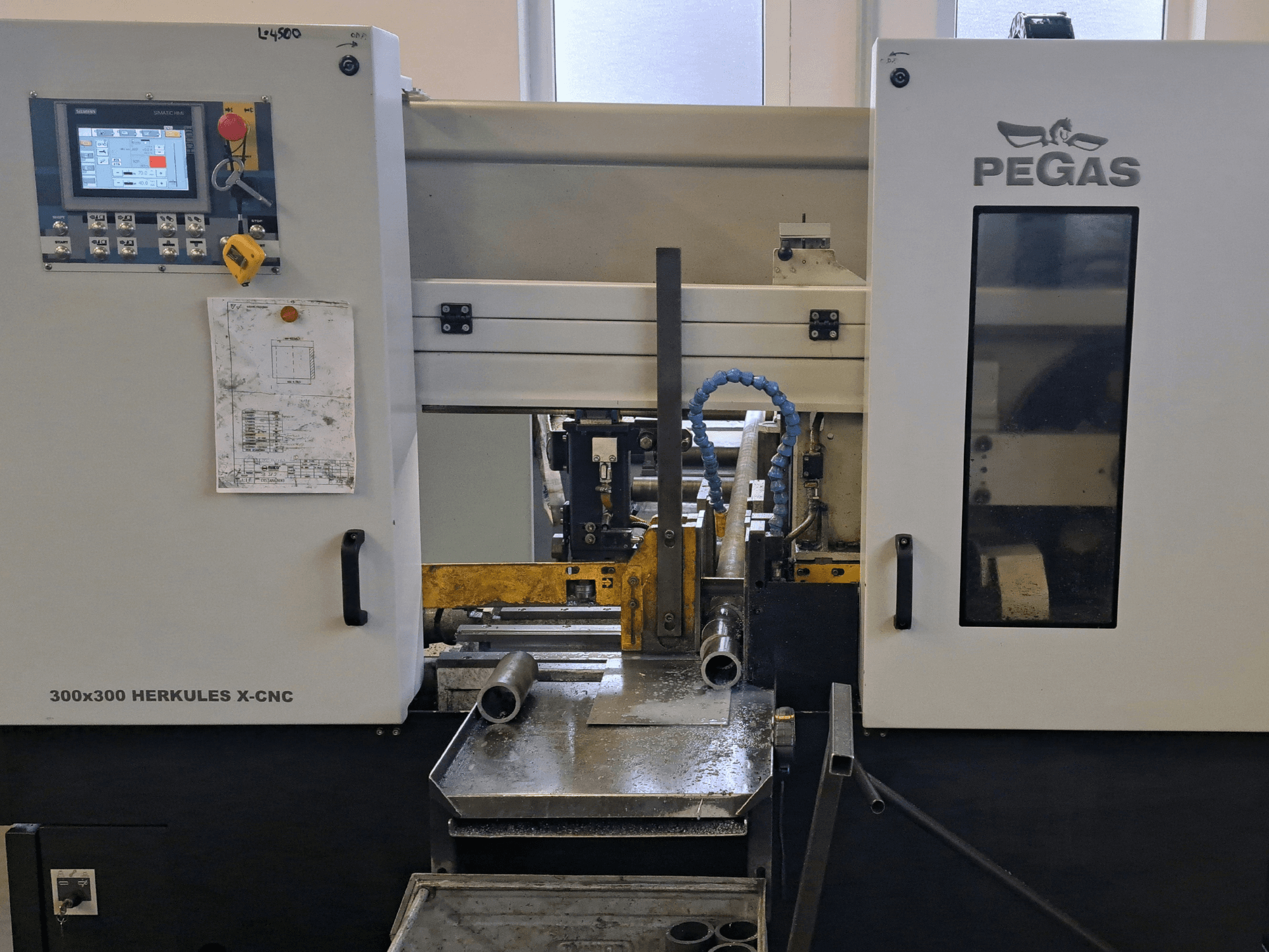 Станок для обработки листового металла Pegas HERKULES X-CNC 300x300, вид спереди, на котором видны панель управления и рабочая зона с металлическими заготовками.