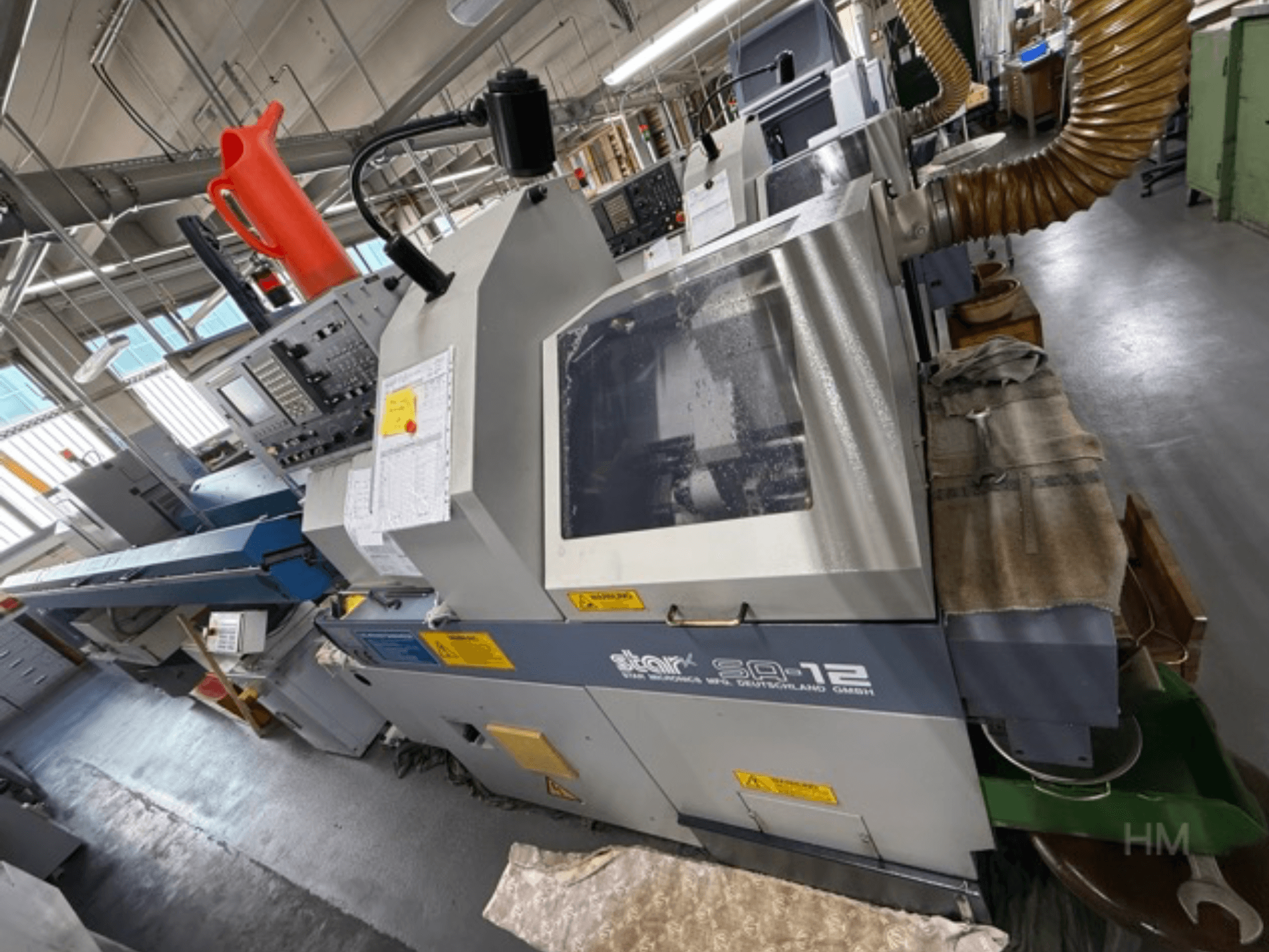 Обрабатывающий центр Star SQ-12, вид сбоку с панелью управления, контейнером для охлаждающей жидкости и шлангом для удаления пыли.