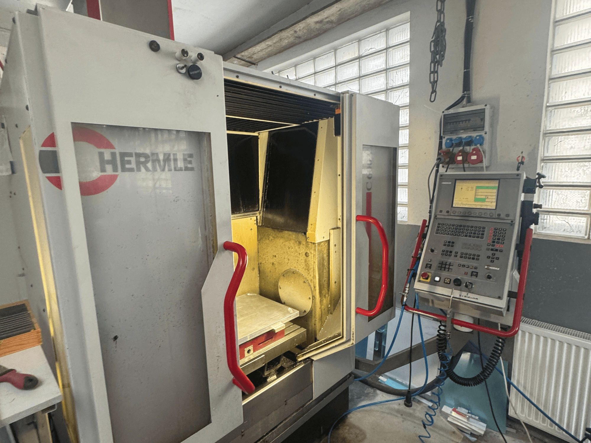 Вертикальный обрабатывающий центр HERMLE C600V, вид спереди с открытой дверью, панелью управления и внутренней рабочей зоной.