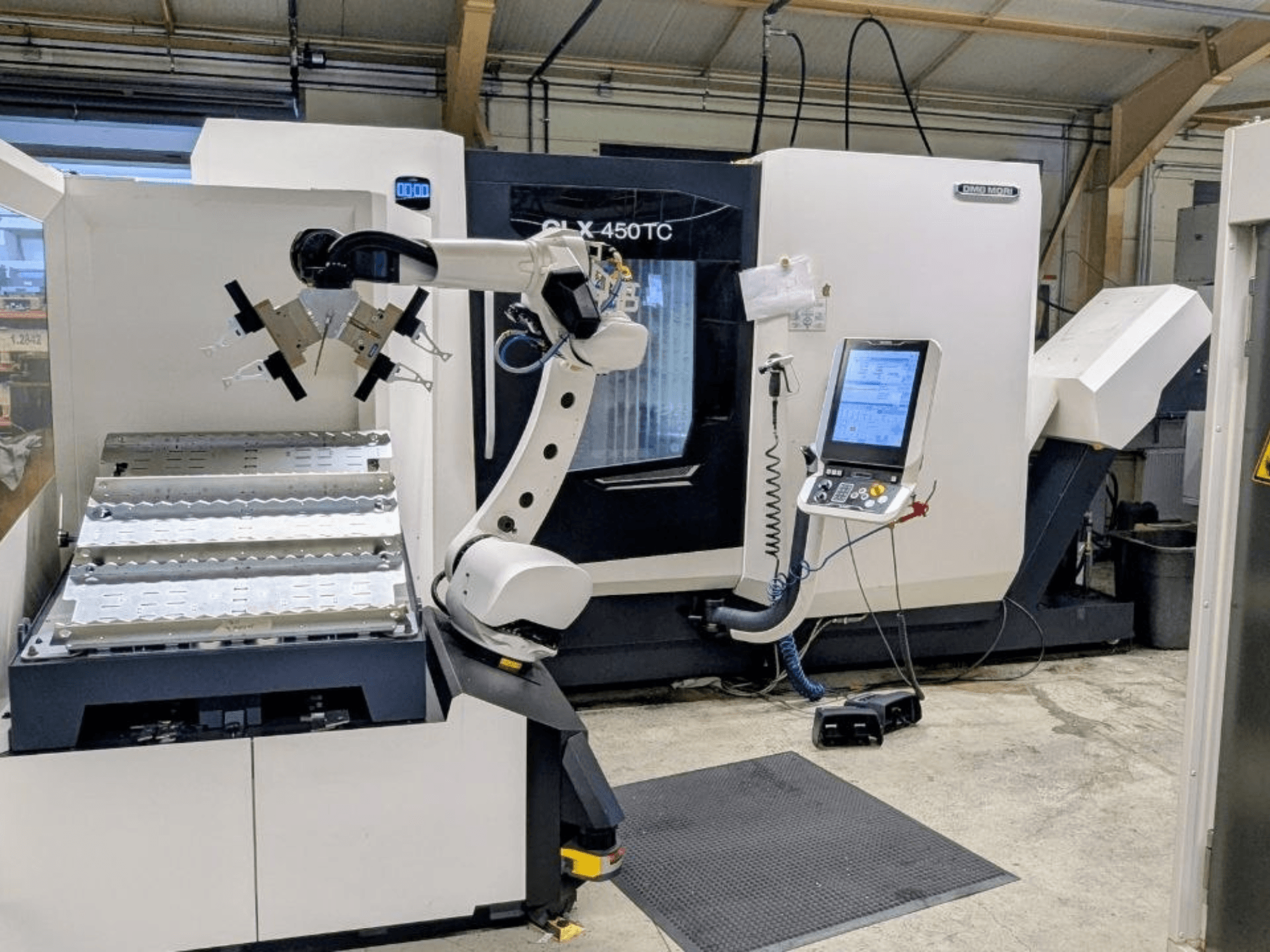 DMG MORI CLX 450 TC с системой Robo2go, вид спереди, на котором видны манипулятор и панель управления, расположенные рядом со станком.
