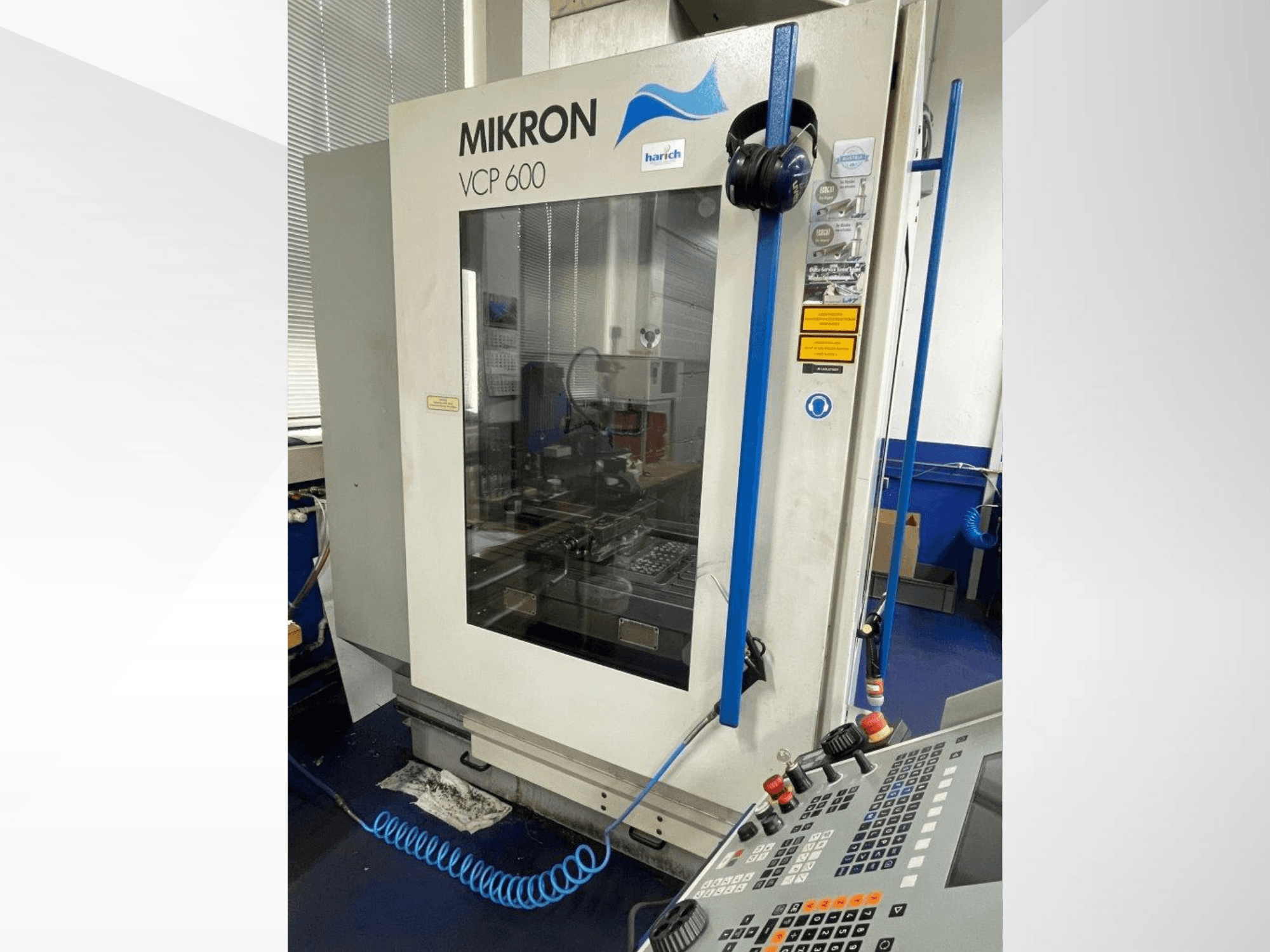Станок с ЧПУ Mikron VCP 600, вид спереди, панель управления с кнопками и видимая зона обработки за стеклом.