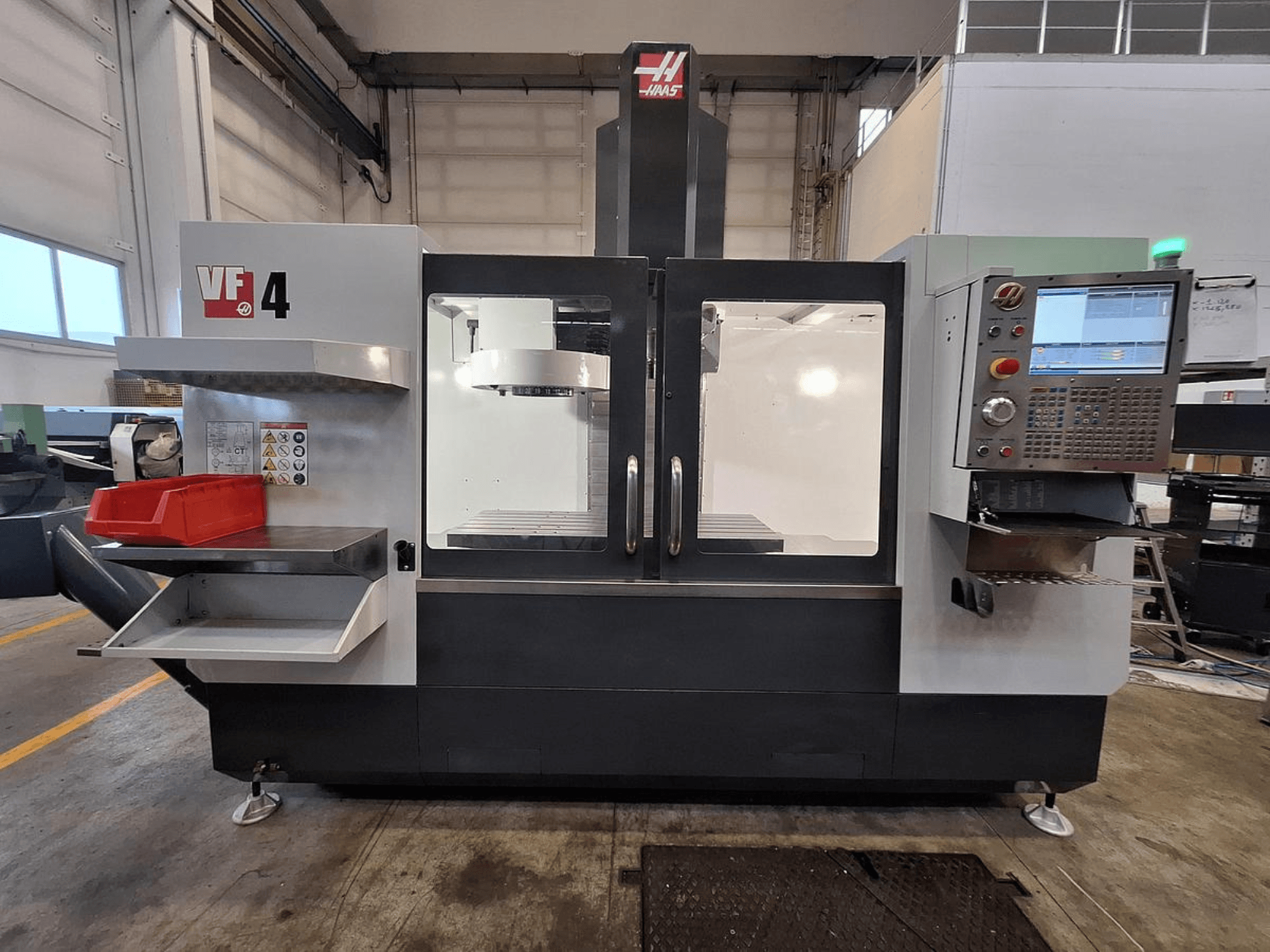Вертикальный обрабатывающий центр Haas VF-4, вид спереди, с панелью управления, держателем инструмента и просторной рабочей зоной.