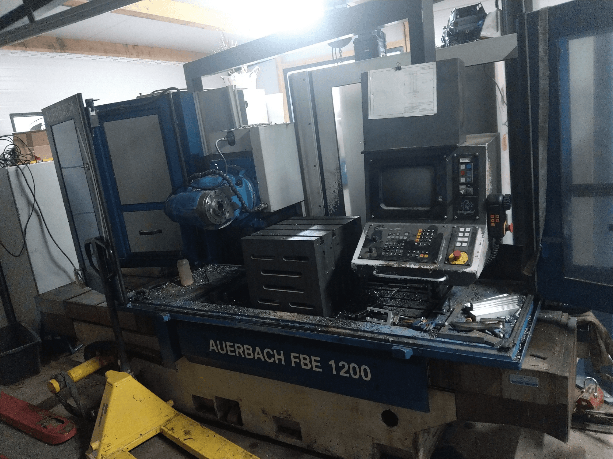 Сверлильный станок по металлу Auerbach FBE 1200, вид спереди, видна панель управления, двигатель и металлическая стружка на рабочей поверхности.