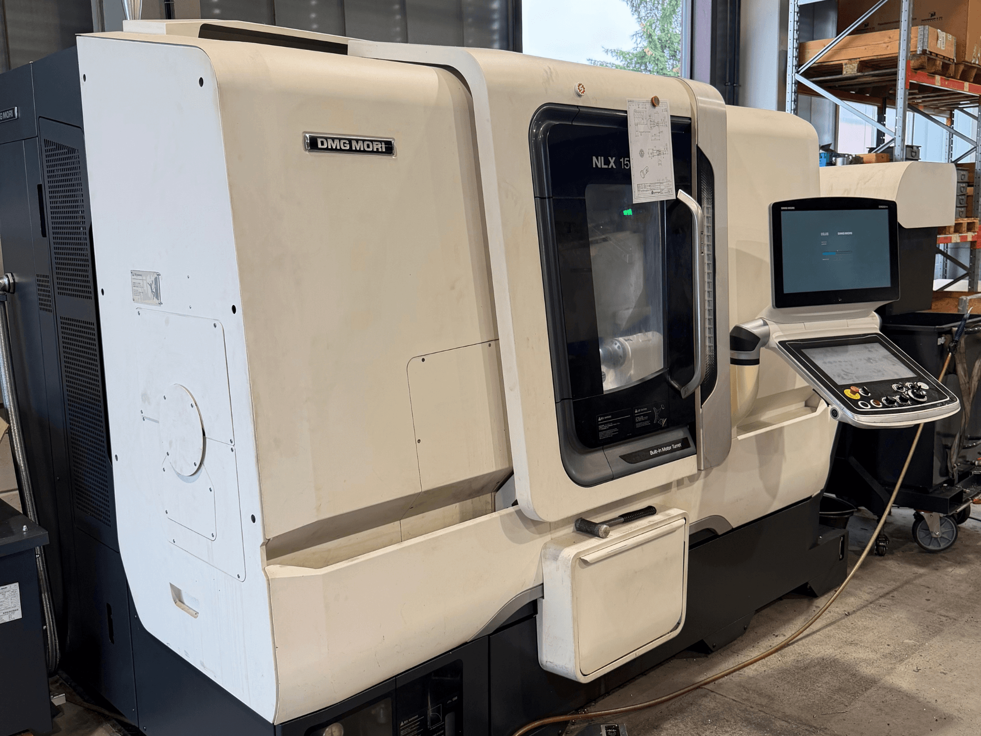 Вид спереди горизонтального токарного станка DMG MORI NLX1500MC/500, на котором через прозрачную крышку видны панель управления и зона шпинделя.