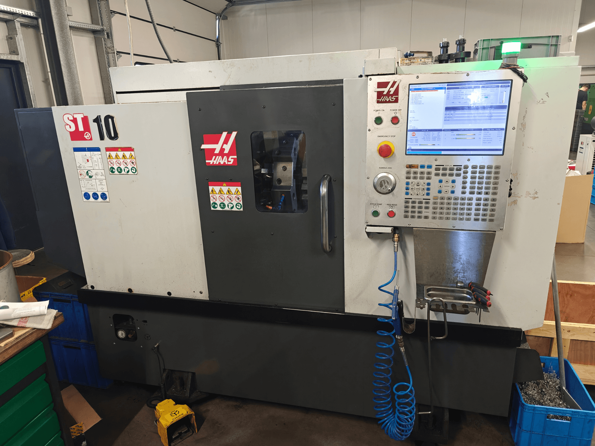 Горизонтальный токарный станок Haas ST-10, вид спереди, на котором видны панель управления, предупреждающие надписи и конструкция станка.