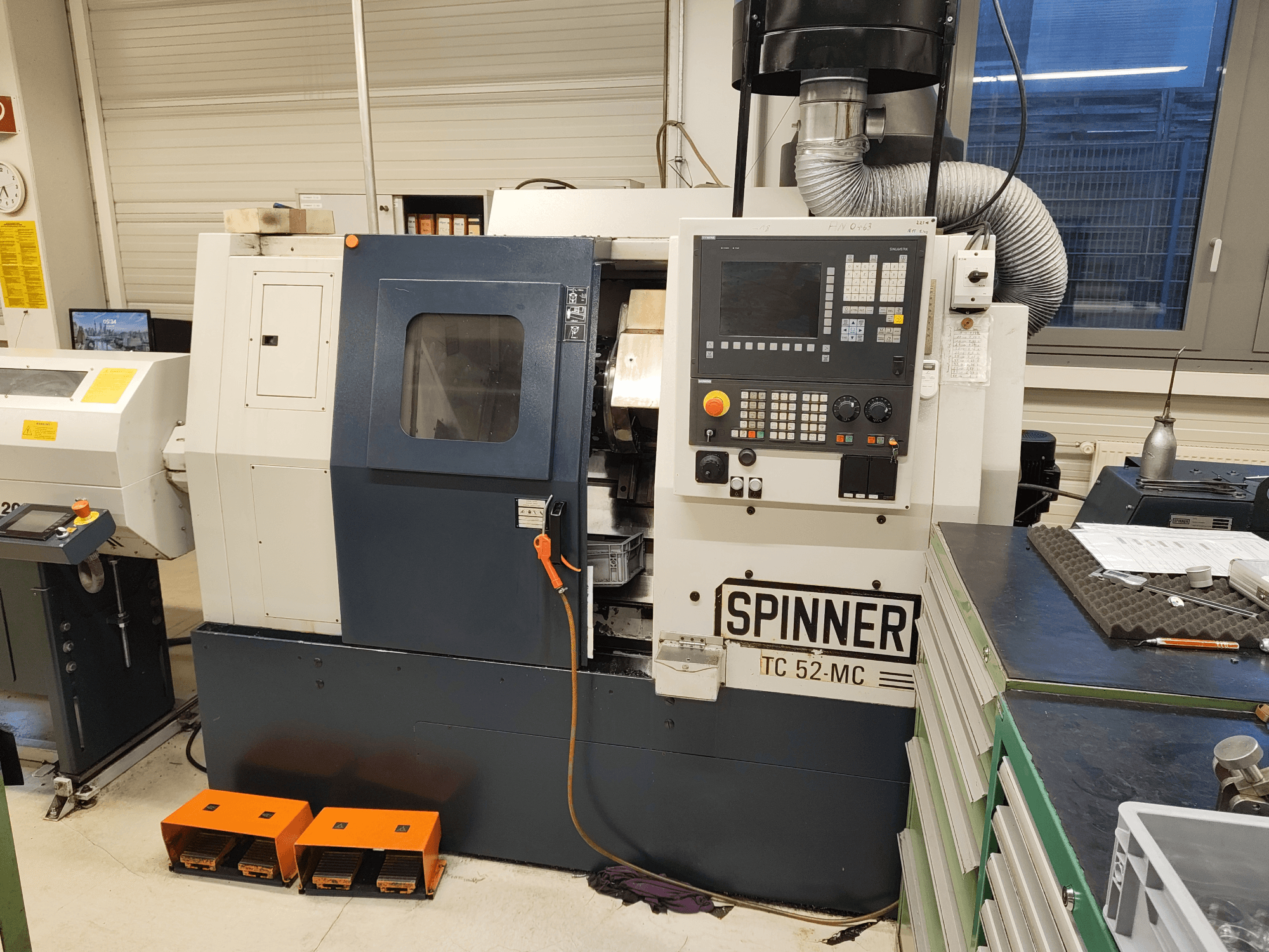 Горизонтальный токарный станок SPINNER TC 52 MC в цехе, вид спереди, на котором видны панель управления, зона обработки и средства безопасности.