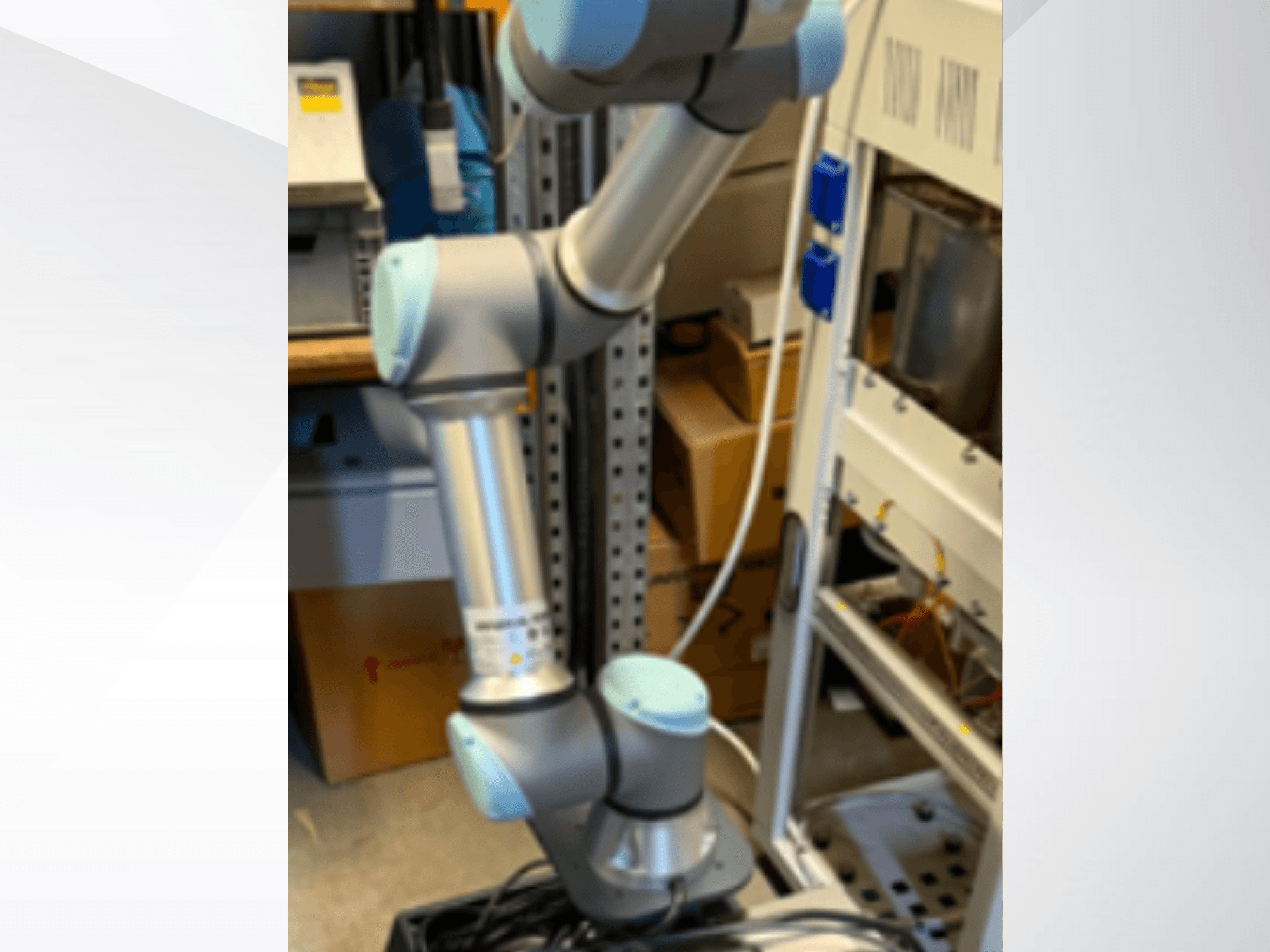 Роботизированный манипулятор Universal Robots UR5e, вид сбоку: видны шарнирные соединения, облегченная конструкция и кабели управления.