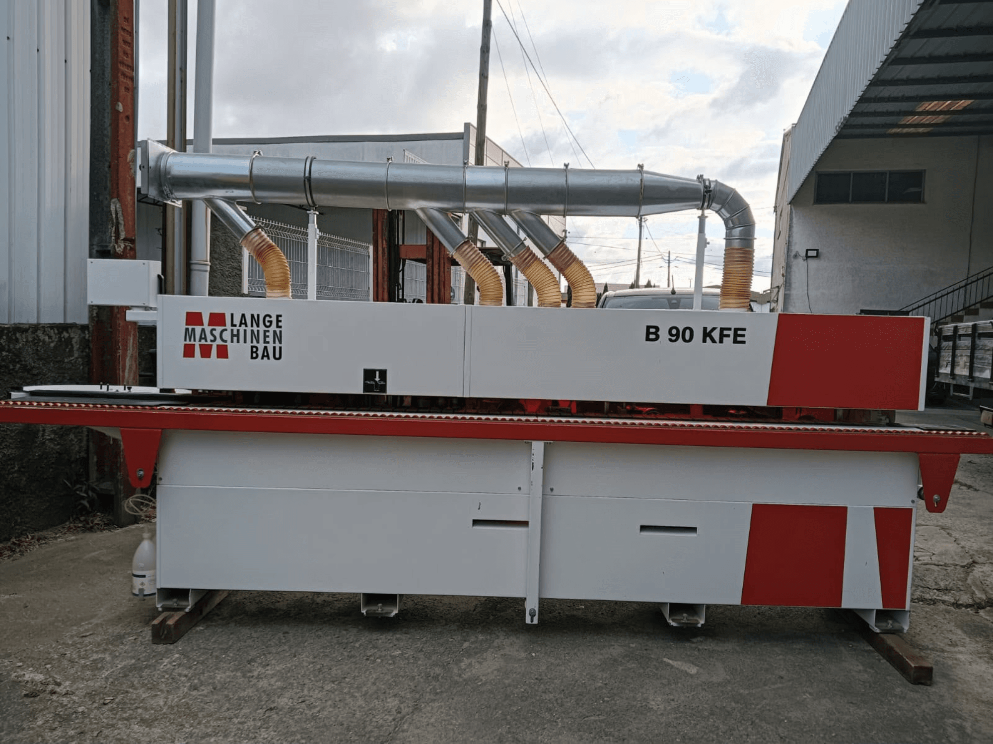 Кромкооблицовочная машина LANGE Maschinenbau B 90 KFE в боковом ракурсе с двумя выхлопными трубами и красными акцентами, установленная в промышленном цехе.