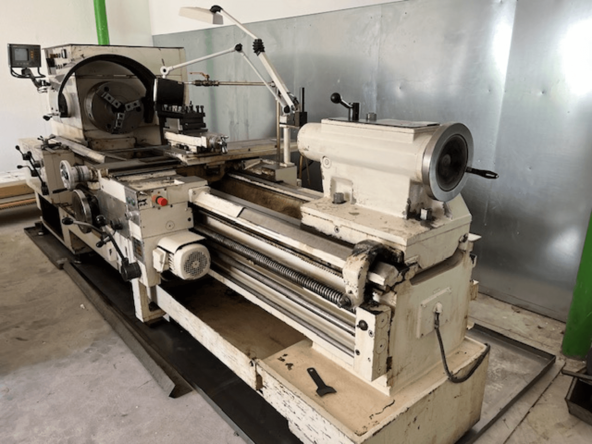 Винтажный токарный станок по металлу с панелью управления и инструментами, вид сбоку, демонстрирующий рабочие элементы и отделку металла.