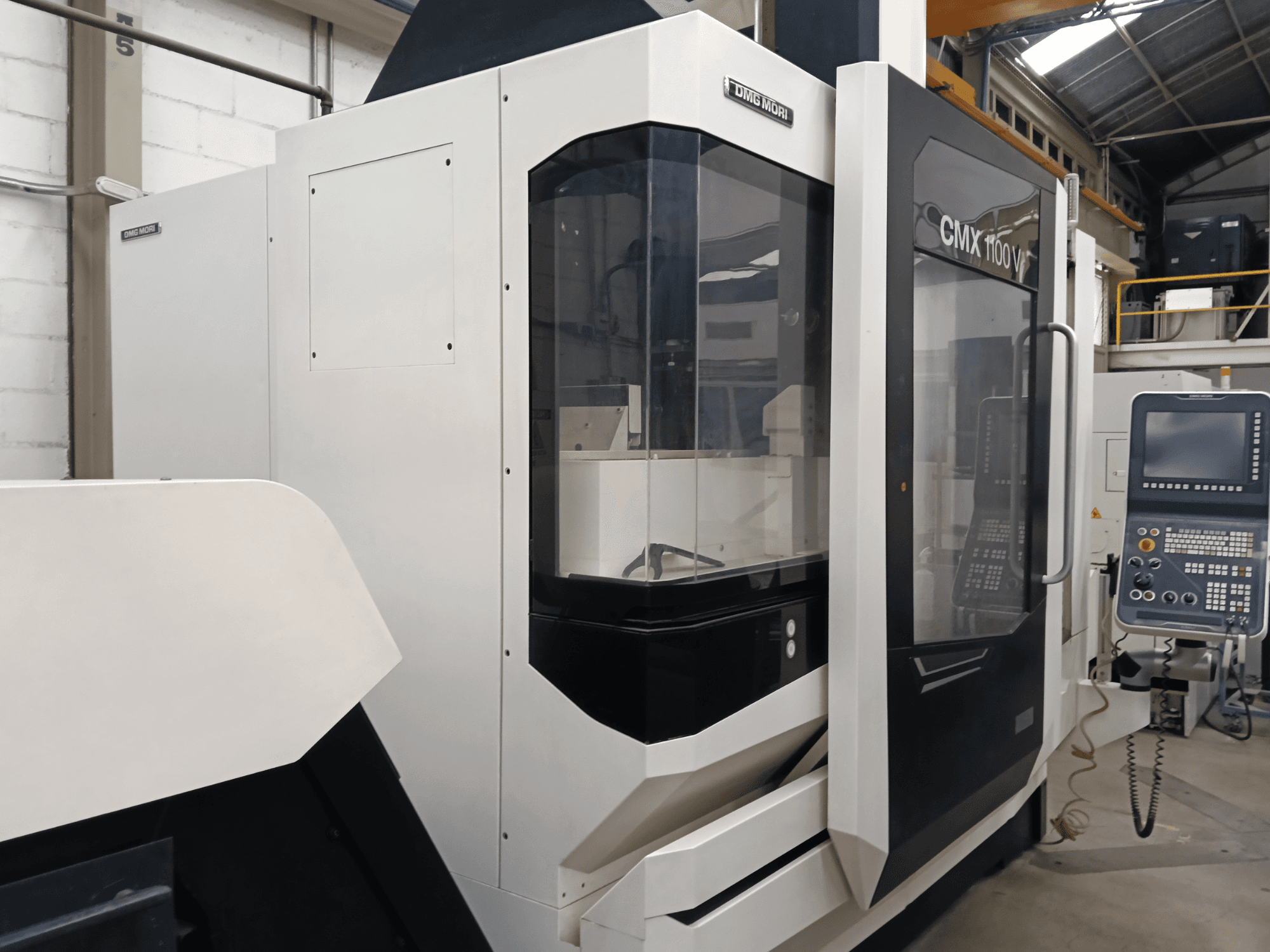 Вертикальный обрабатывающий центр DMG MORI CMX 1100 V, вид спереди, на котором видны панель управления и стеклянный кожух.