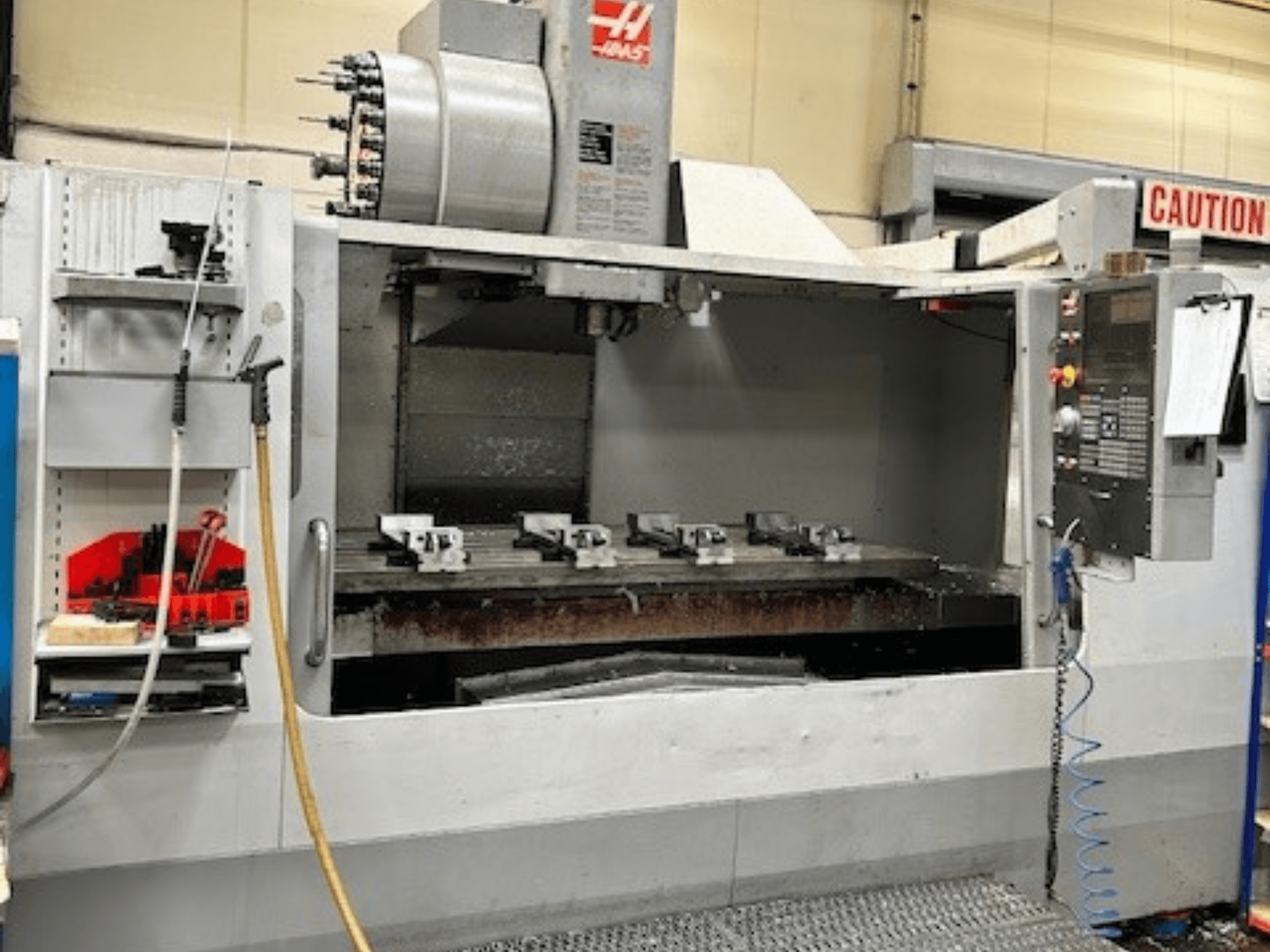 Вертикальный обрабатывающий центр HAAS VF-9/40HE, вид спереди, сбоку видны держатель инструмента и принадлежности.