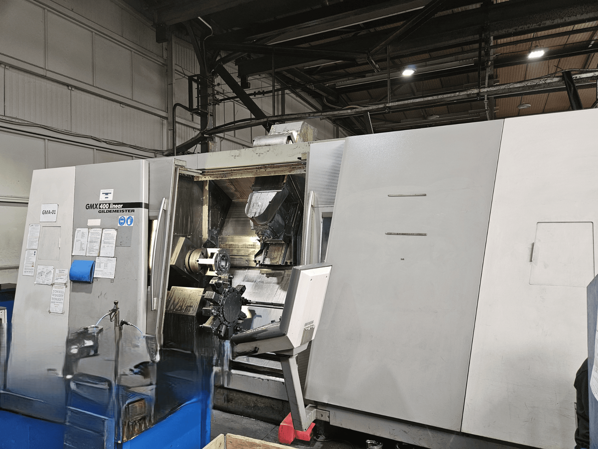 Токарно-фрезерный центр Gildemeister GMX 400 Linear спереди, демонстрирующий открытый доступ к зоне обработки и инструментам внутри.