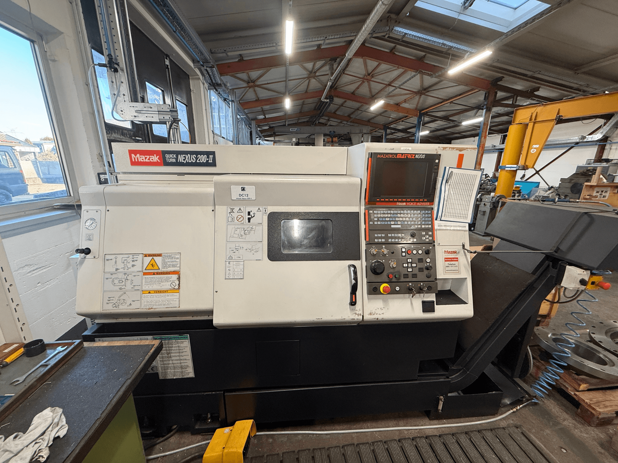 Горизонтальный токарный станок Mazak QUICK TURN NEXUS 200-II, вид спереди, с изображением панели управления и рабочих элементов.